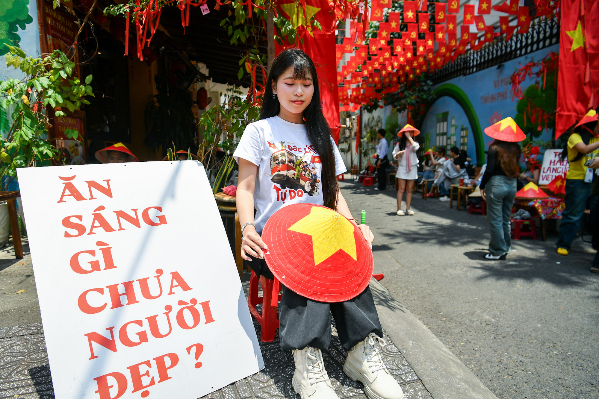 Một cô gái chụp ảnh với chiếc nón lá sơn cờ đỏ sao vàng