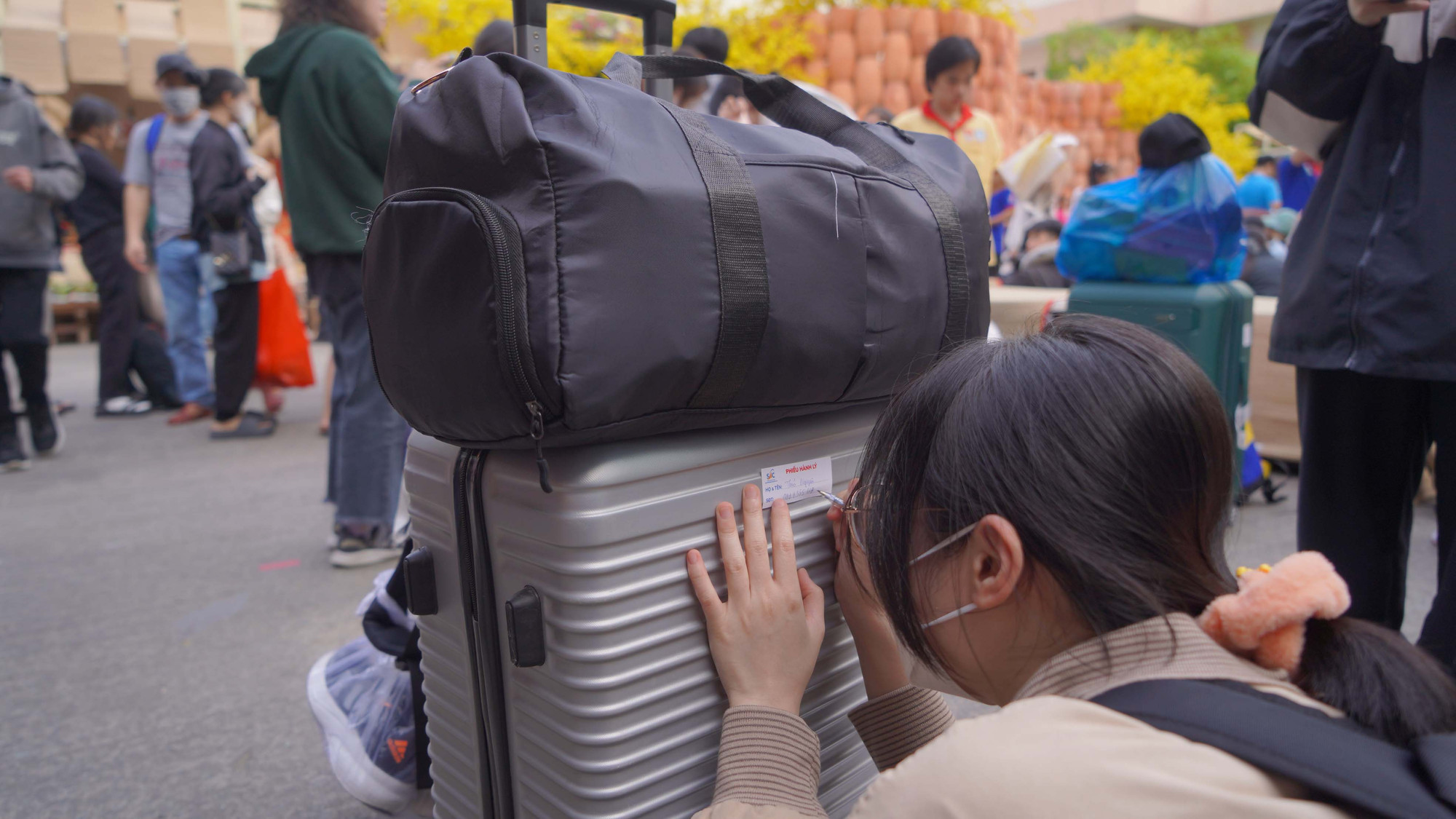 Các sinh viên ghi lại tên trên hành lý của mình.