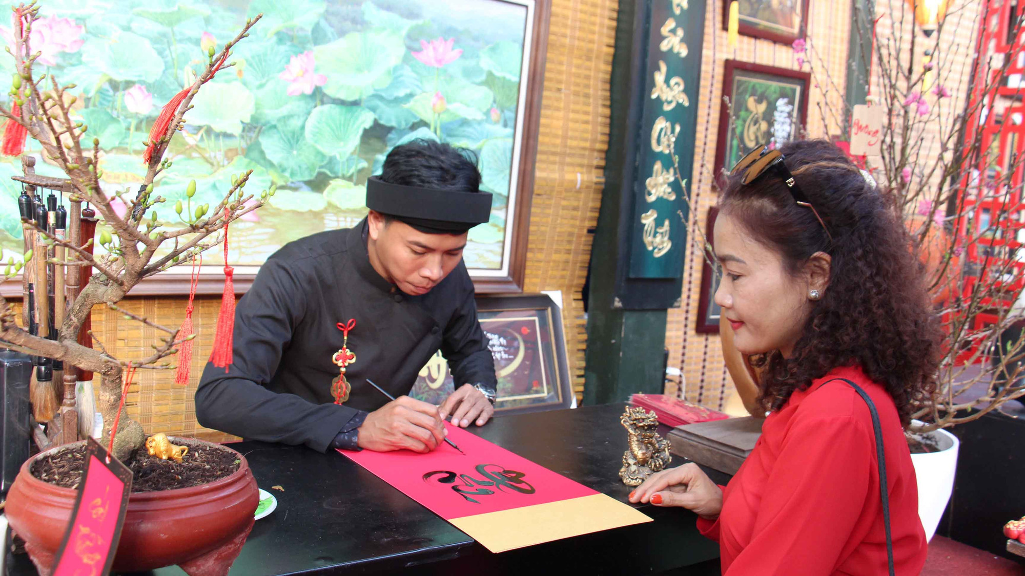 Một số gian hàng đã bày bán các bức thư pháp viết sẵn sau khi hoàn tất phần trang trí. Gian hàng được bài trí cầu kỳ với tranh linh vật rồng, bức thư pháp, tượng, đào mai khoe sắc...