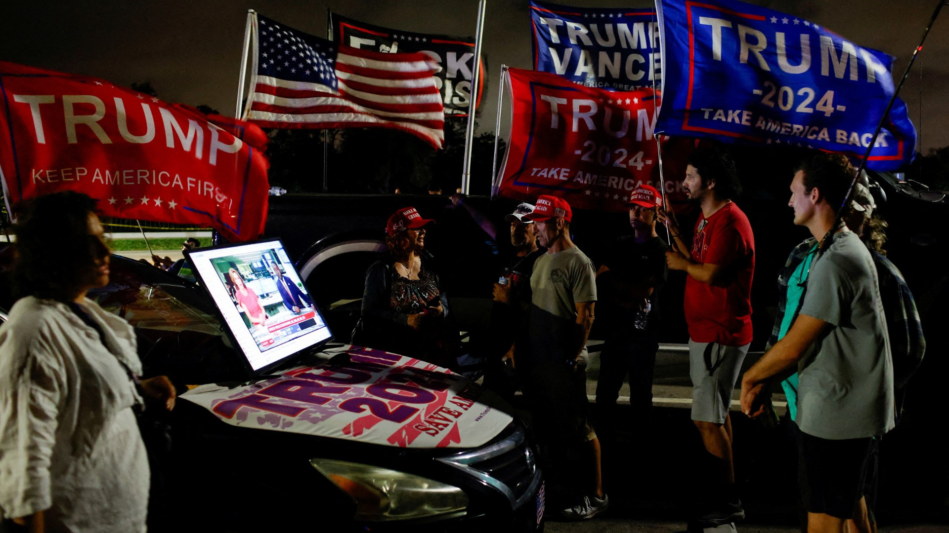 Những người ủng hộ ông Trump theo dõi tin tức bầu cử trên màn hình kết nối với ô-tô trong ngày bầu cử 5/11, Palm Beach, Florida.