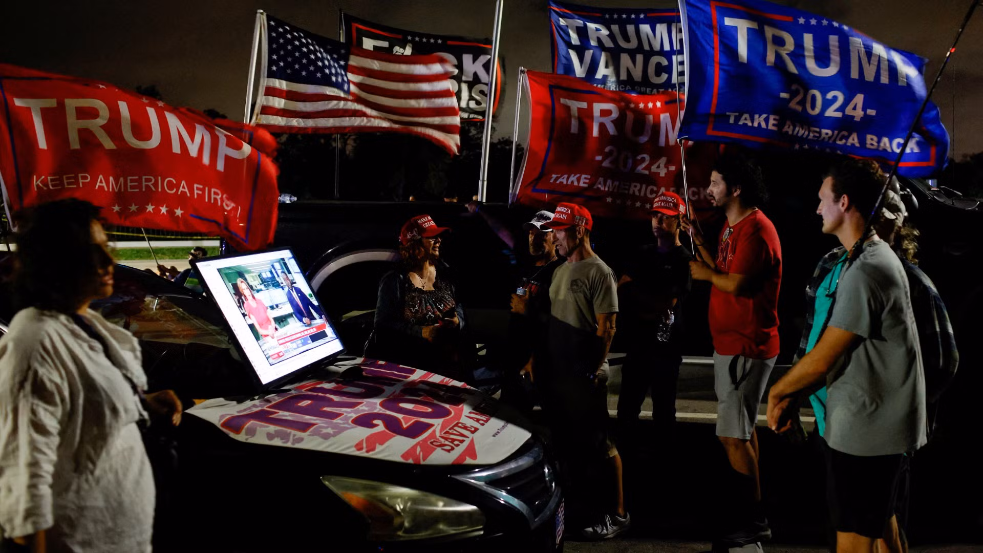 Những người ủng hộ ông Trump theo dõi tin tức bầu cử trên màn hình kết nối với ô-tô trong ngày bầu cử 5/11, Palm Beach, Florida.