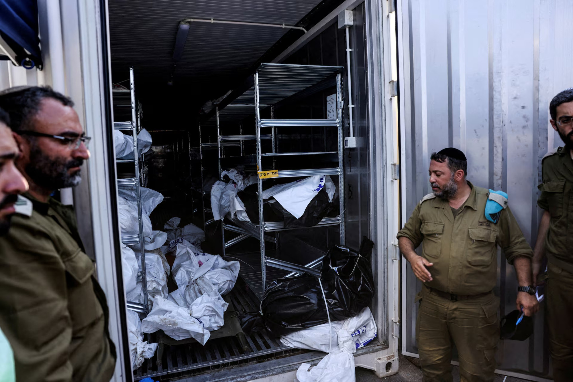 Các sĩ quan quân đội Israel đứng cạnh một container bảo quản thi thể của những người thiệt mạng trong khi chờ người thân đến nhận dạng, Ramla, Israel, ngày 13/10/2023. (Ảnh: Reuters) Các sĩ quan quân đội Israel đứng cạnh một container bảo quản thi thể của những người thiệt mạng trong khi chờ người thân đến nhận dạng, Ramla, Israel, ngày 13/10/2023. (Ảnh: Reuters)