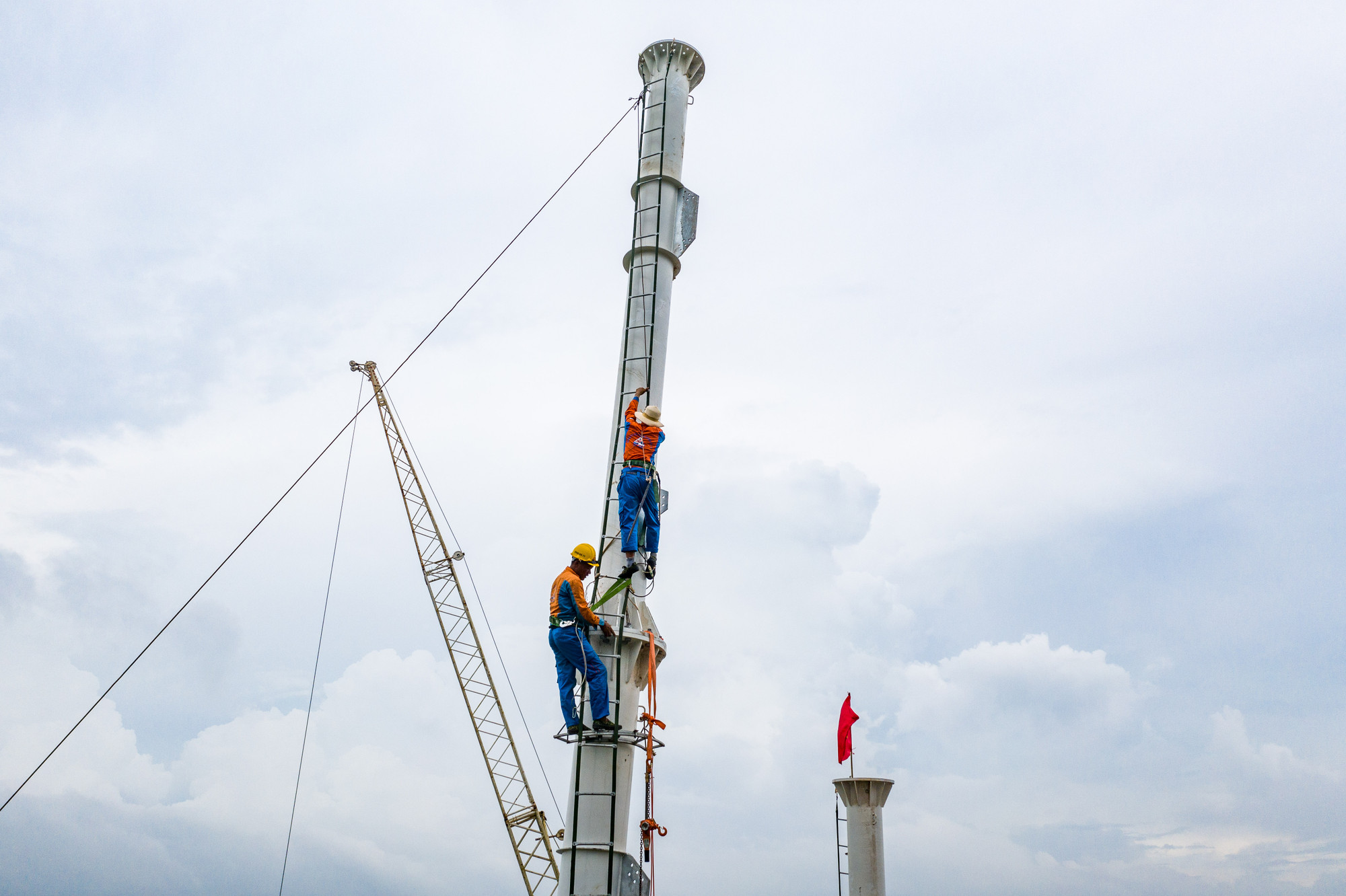 Ở các vị trí cao nhất mà cẩu đã tới giới hạn, công nhân phải sử dụng thêm thang dây để di chuyển và lắp đặt các cấu kiện trên điểm cao. (Ảnh: THÀNH ĐẠT)