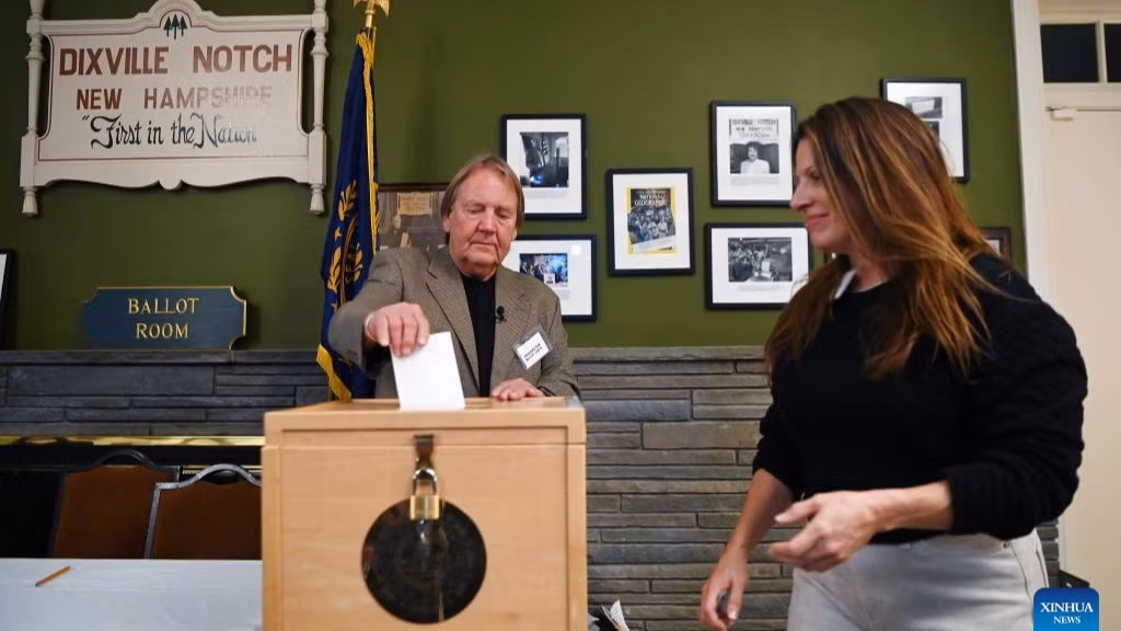 Nhân viên điều phối giúp một nữ cử tri (bìa phải) bỏ phiếu tại Dixville Notch, New Hampshire trong ngày bầu cử tổng thống Mỹ, 5/11/2024. (Ảnh: Xinhua)