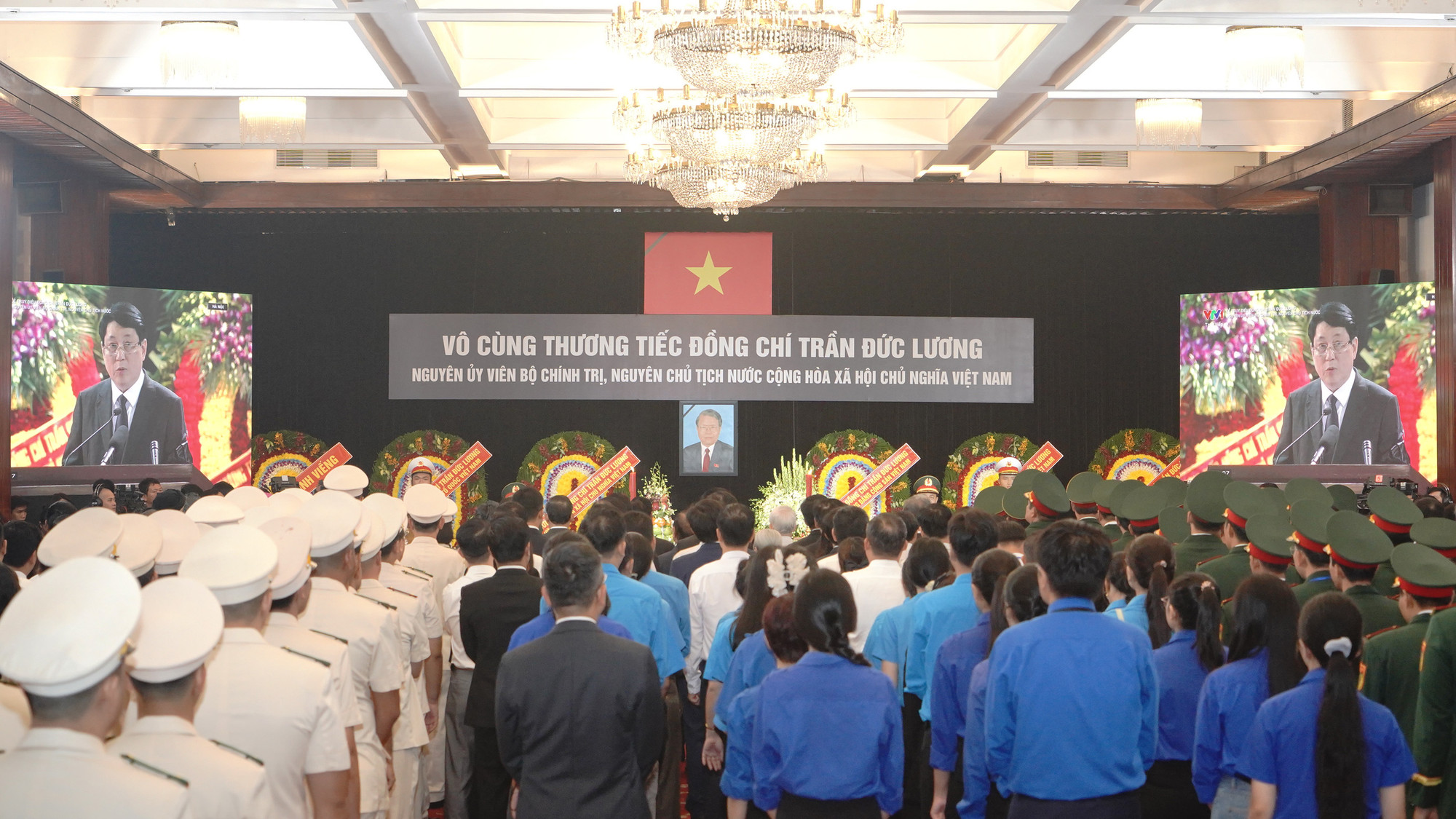 Mọi người cùng hướng về màn hình lớn trong Hội trường, theo dõi Lễ truy điệu được truyền hình trực tiếp từ Nhà tang lễ Quốc gia, Hà Nội. Đúng 7 giờ sáng, Lễ truy điệu nguyên Chủ tịch nước Trần Đức Lương tại Thành phố Hồ Chí Minh chính thức bắt đầu trong không khí trang nghiêm và xúc động.