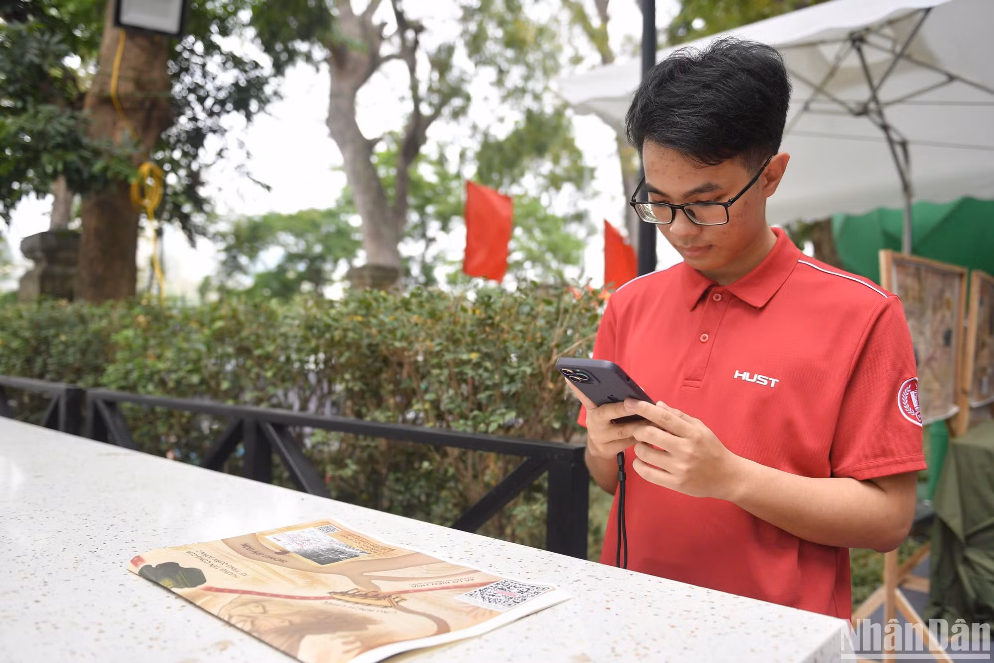 Em Đào Quang Đức trải nghiệm quét mã QR trên phụ san đặc biệt của Báo Nhân Dân. (Ảnh: THẾ ĐẠI)