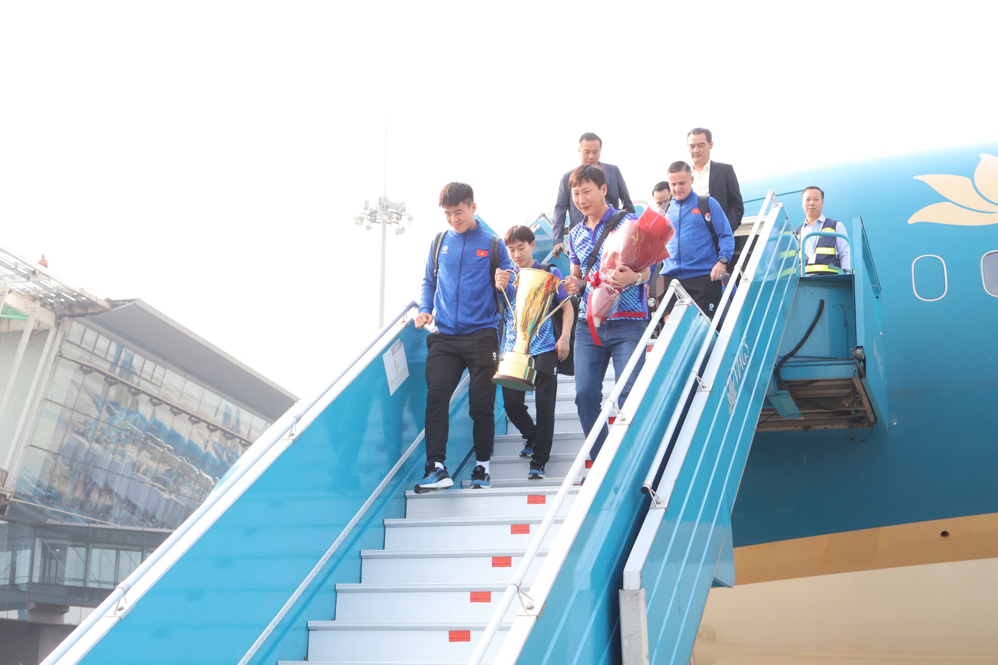 Huấn luyện viên Kim Sang-sik cùng đội trưởng Duy Mạnh mang cúp xuống máy bay.