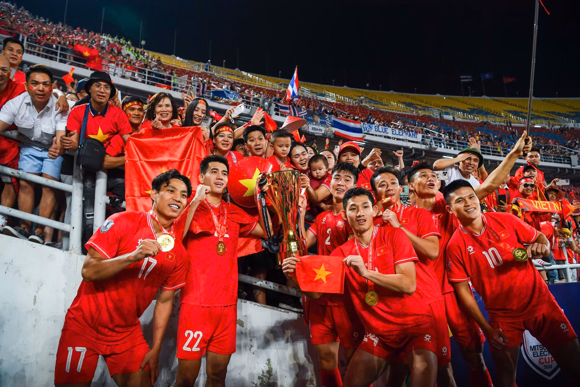 Đội tuyển Việt Nam chụp hình cúp vô địch cùng người hâm mộ đã "tiếp lửa" cho đội tuyển tại sân vận động Rajamangala. Đội tuyển Việt Nam chụp hình cúp vô địch cùng người hâm mộ đã "tiếp lửa" cho đội tuyển tại sân vận động Rajamangala.