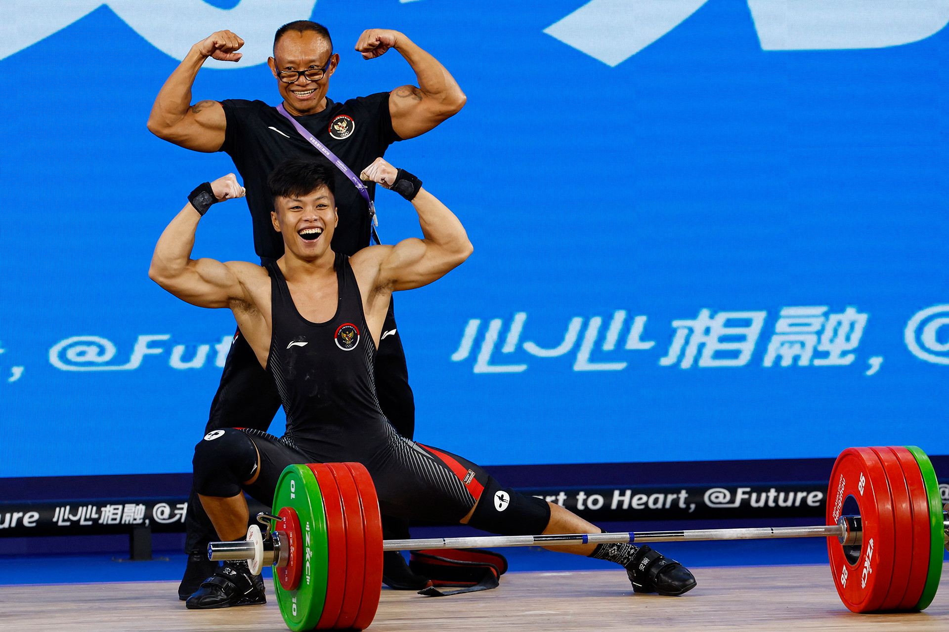 Vận động viên Indonesia Abdullah Rahmat Erwin ăn mừng cùng huấn luyện viên sau khi lập kỷ lục thế giới mới ở hạng cân 73kg nam, tại ASIAD Hàng Châu 2023. (Ảnh: Reuters)