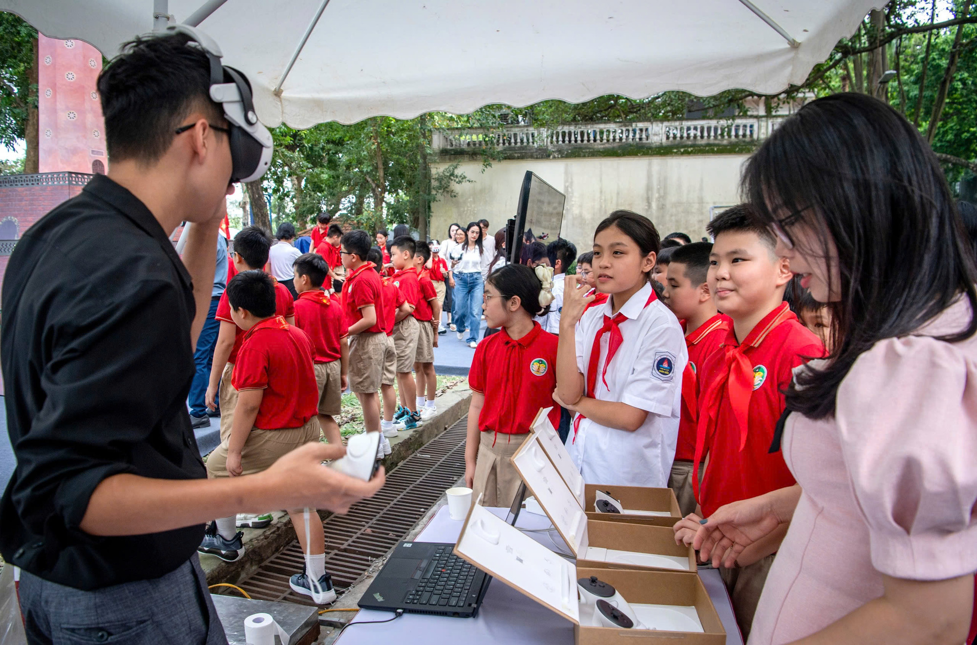 Ban tổ chức hướng dẫn các em học sinh trải nghiệm kính thực tế ảo tăng cường (AR) xem hình ảnh 3D về Hà Nội.