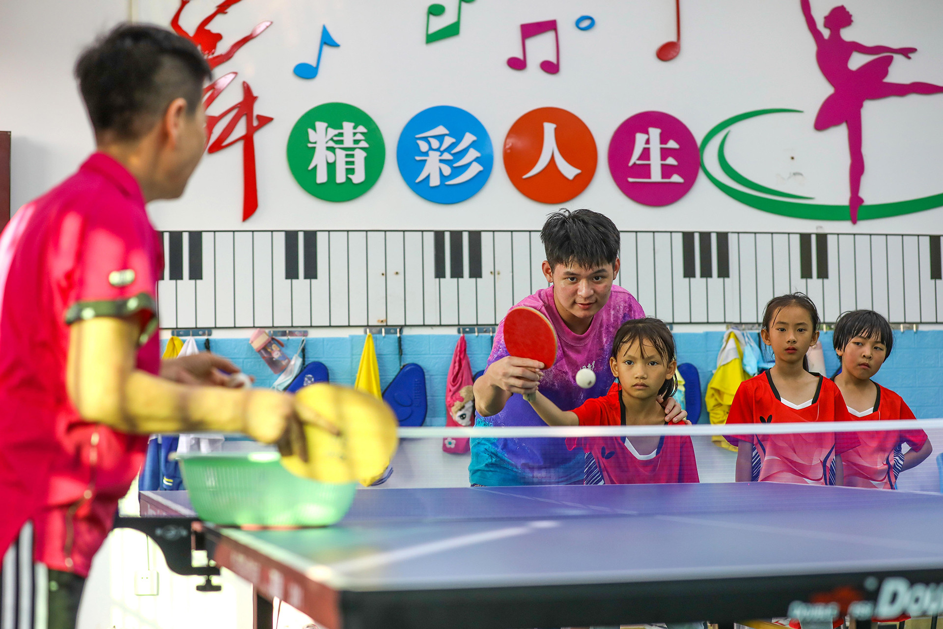 Vận động viên đội tuyển bóng bàn quốc gia Trung Quốc Lin Shidong dạy trẻ em cách giao bóng tại Trường trung tâm Shuiman ở thành phố Ngũ Chỉ Sơn, tỉnh Hải Nam. (Ảnh: China Daily)