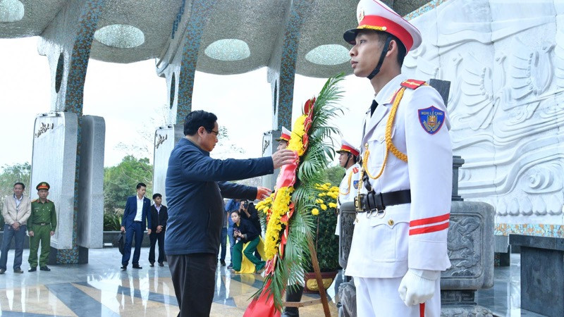 Thủ tướng Phạm Minh Chính chỉnh vòng hoa để thực hiện nghi thức tưởng niệm các Anh hùng liệt sĩ tại tượng đài trong Nghĩa trang Liệt sĩ tỉnh Quảng Nam. (Ảnh: THANH GIANG)
