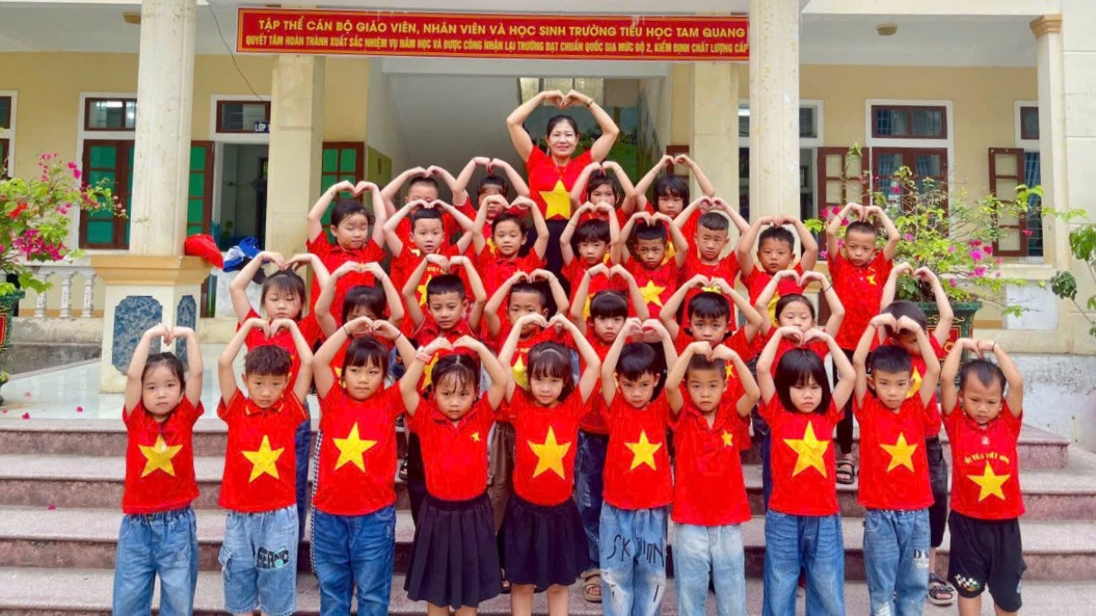 Giáo viên và các em học sinh cùng nhau lưu lại khoảnh khắc đáng nhớ trong trang phục áo đỏ sao vàng.