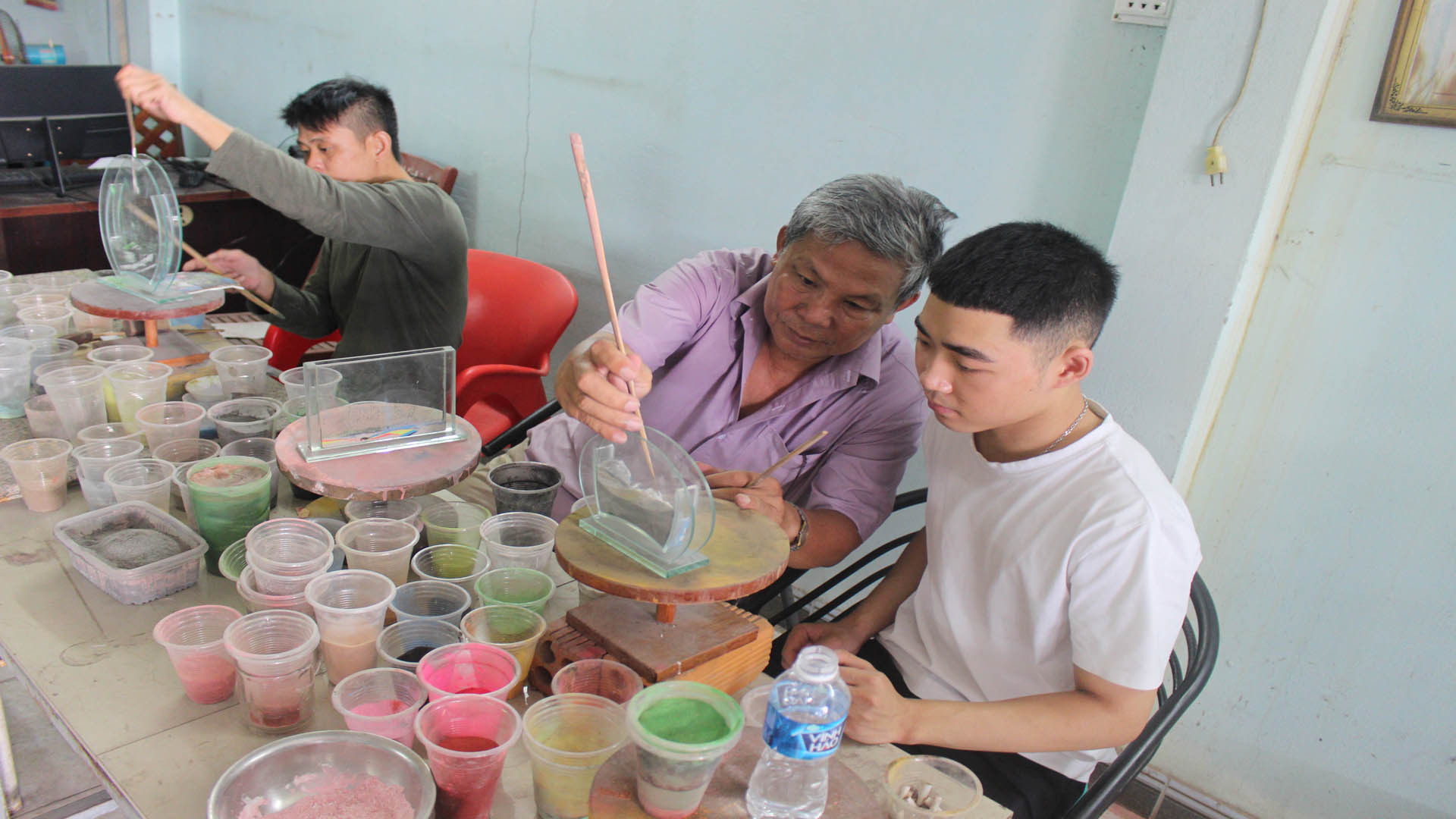 Anh Đặng Minh Nghĩa hướng dẫn trẻ khuyết tật làm tranh cát tại phòng tranh Minh Tuấn, thành phố Phan Rang - Tháp Chàm, tỉnh Ninh Thuận.