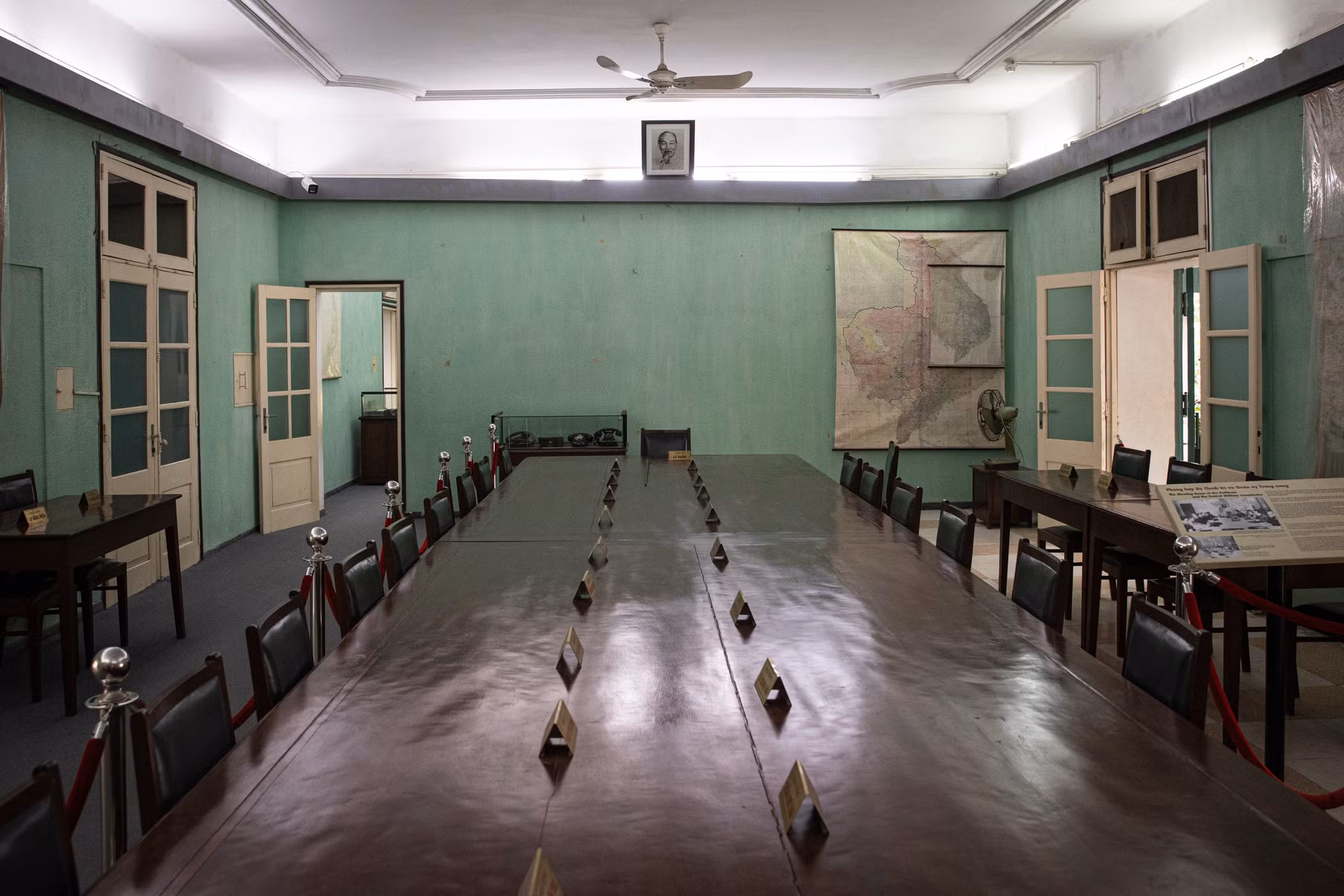 Bàn họp đặt tại vị trí trung tâm của phòng, nhìn theo hướng đông-tây. Hai phía bắc-nam của phòng có 4 bàn nhỏ, là vị trí ngồi của thư ký các cuộc họp. Hiện nay, trên mặt bàn đang sắp xếp các biển đồng đề tên 24 đồng chí đã từng tham gia cuộc họp Bộ Chính trị mở rộng cuối năm 1974 đầu năm 1975.