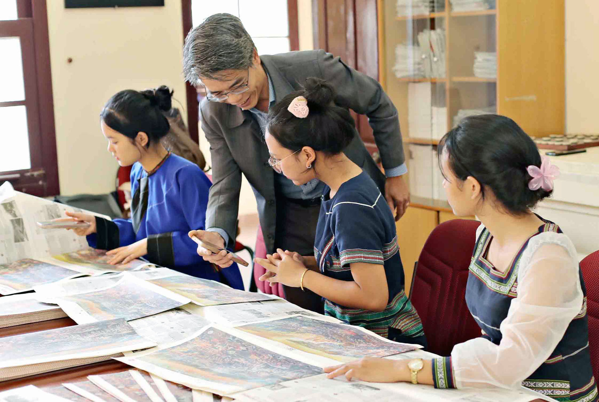 Đại diện Báo Nhân Dân tại Lâm Đồng hướng dẫn các em học sinh quét mã QR trải nghiệm ấn phẩm tranh panorama.