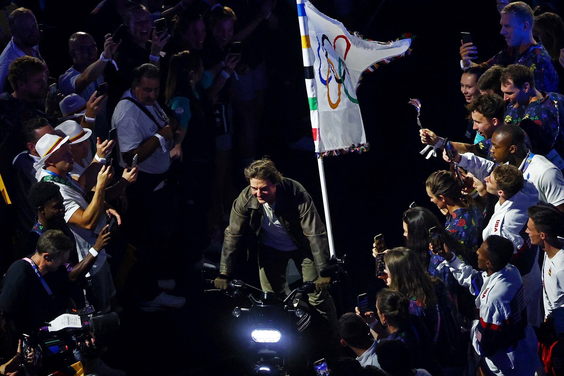 Nam tài tử Hollywood Tom Cruise mang theo Lá cờ Olympic trên chiếc mô-tô phân khối lớn tiến vào sân vận động.