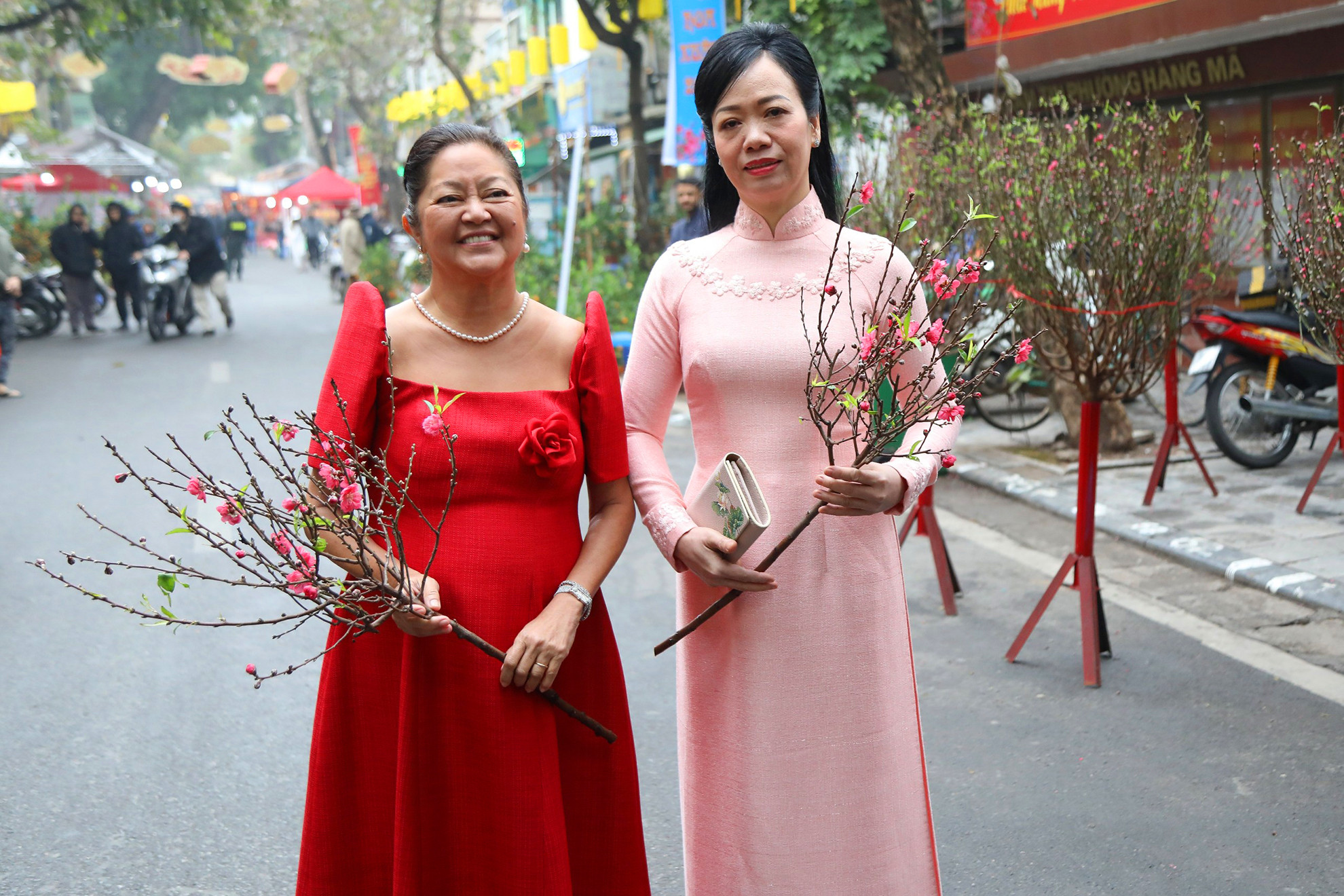 Phu nhân Chủ tịch nước Phan Thị Thanh Tâm và Phu nhân Tổng thống Philippines Louise Araneta Marcos với cành hoa đào ngày Tết tại chợ hoa truyền thống Hàng Lược.