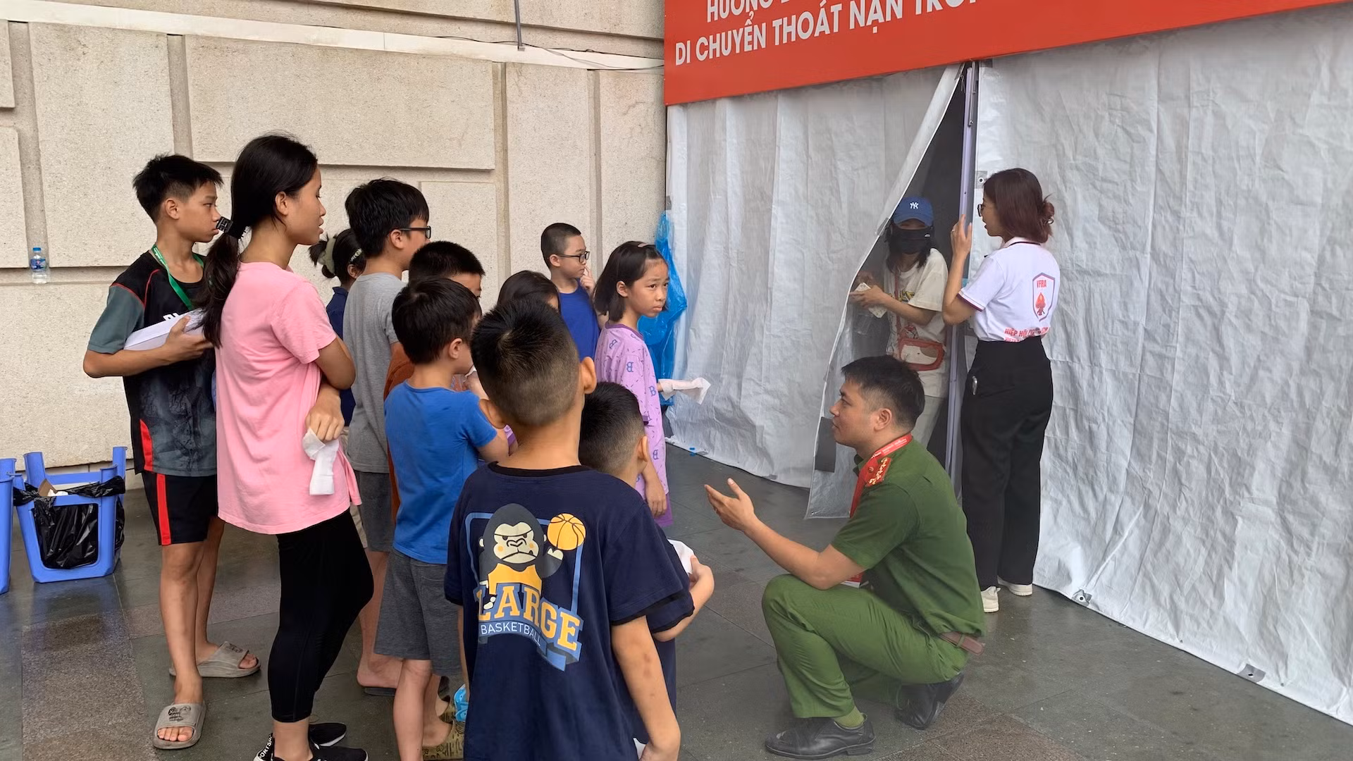 Các em nhỏ chăm chú lắng nghe hướng dẫn thực hành kỹ năng cứu người, di chuyển thoát nạn trong môi trường nhiều khói.