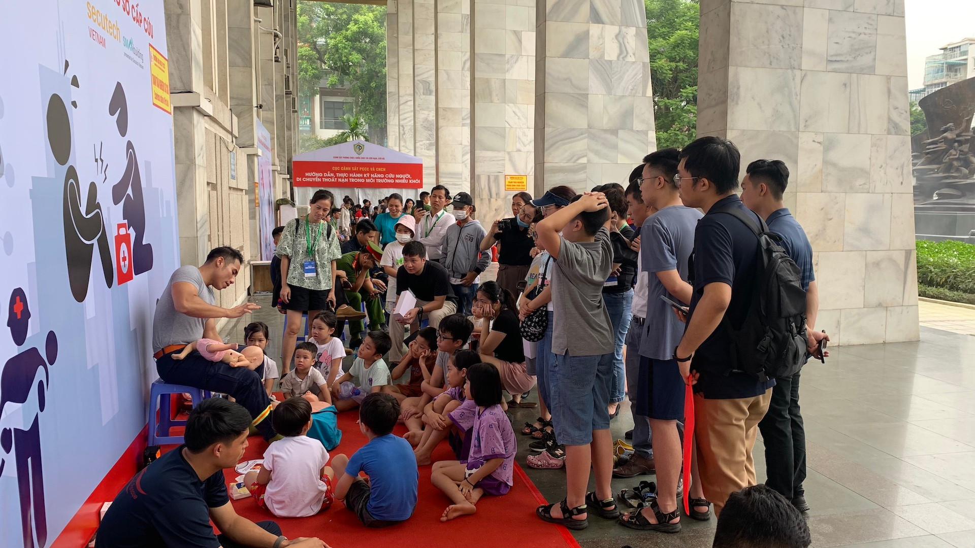 Đông đảo phụ huynh và con em theo dõi hướng dẫn thực hành kỹ năng sơ cấp cứu.