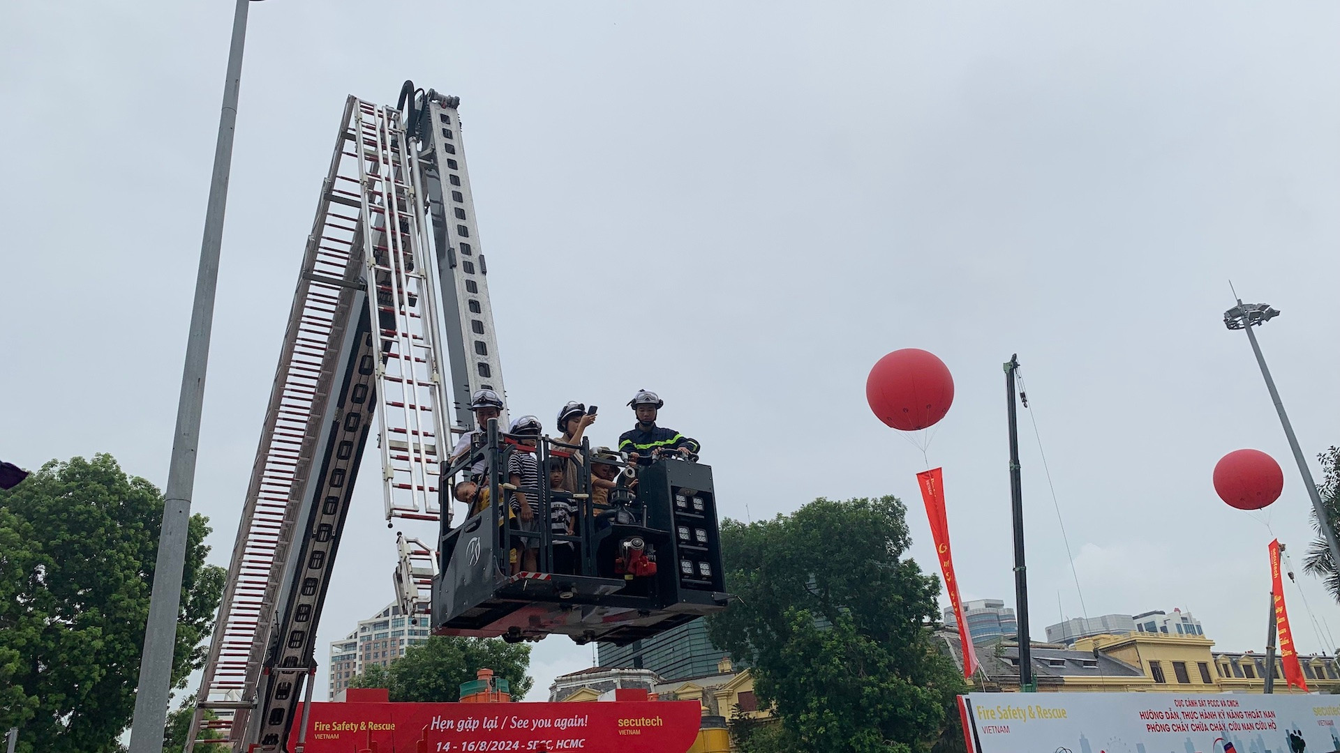 Tham quan và trải nghiệm tất cả các kỹ năng phòng cháy, chữa cháy và thoát nạn tại triển lãm, anh Lê Minh Thắng (Cầu Giấy, Hà Nội) cho biết, đây là lần đầu tiên anh cùng các con được trải nghiệm đầy đủ nhất các kỹ năng phòng cháy, chữa cháy và thoát nạn. "Tôi và hai con đến triển lãm từ sớm, không chỉ các con mà bản thân tôi cũng tham gia trải nghiệm, chúng tôi được các chiến sĩ cảnh sát phòng cháy, chữa cháy hướng dẫn nhiệt tình, tôi học hỏi được rất nhiều, nhất là các kỹ năng thoát nạn khi xảy ra cháy", anh Thắng chia sẻ. Trong ảnh, người dân trải nghiệm thoát nạn bằng xe cẩu chữa cháy.