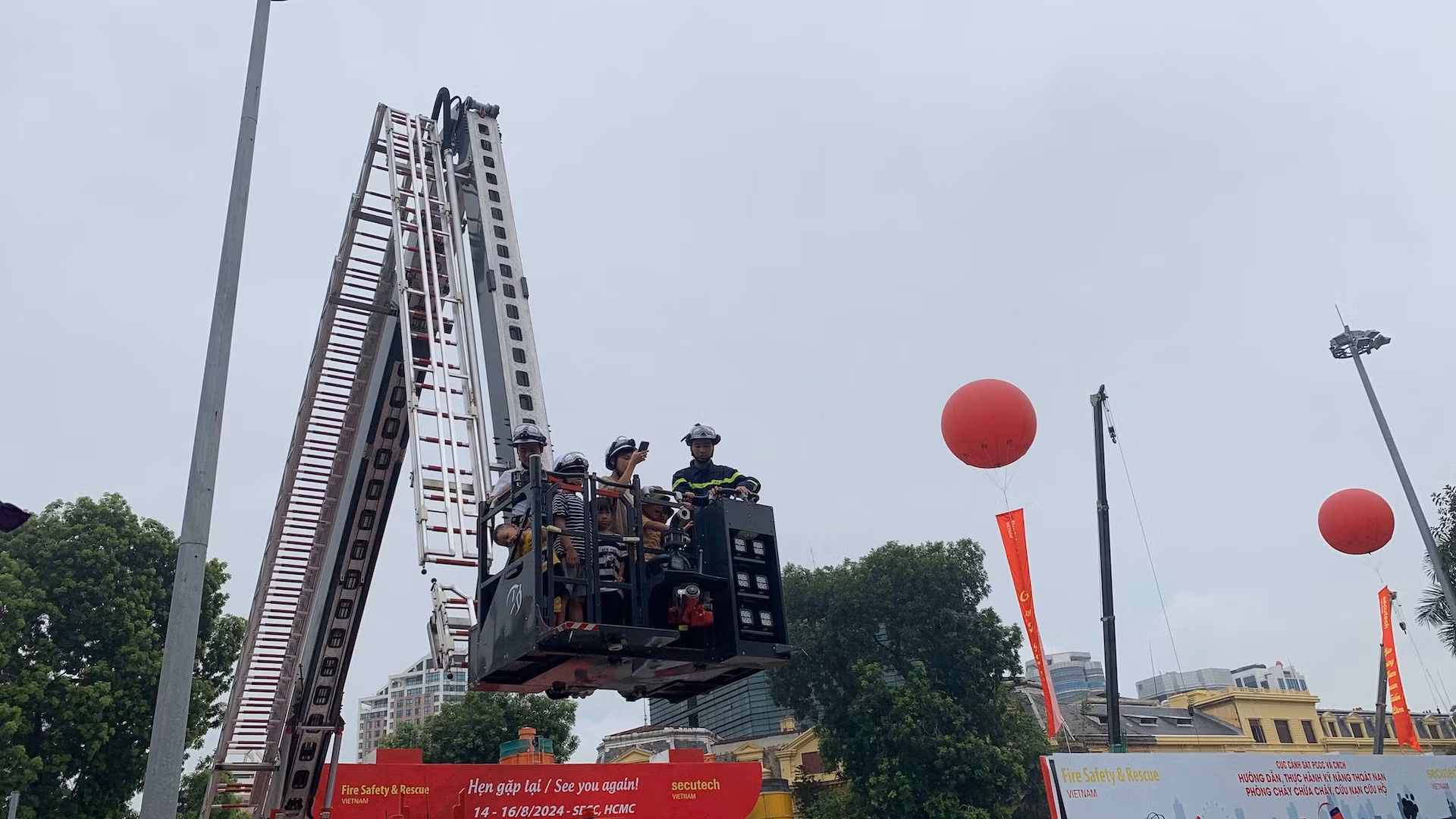 Tham quan và trải nghiệm tất cả các kỹ năng phòng cháy, chữa cháy và thoát nạn tại triển lãm, anh Lê Minh Thắng (Cầu Giấy, Hà Nội) cho biết, đây là lần đầu tiên anh cùng các con được trải nghiệm đầy đủ nhất các kỹ năng phòng cháy, chữa cháy và thoát nạn. "Tôi và hai con đến triển lãm từ sớm, không chỉ các con mà bản thân tôi cũng tham gia trải nghiệm, chúng tôi được các chiến sĩ cảnh sát phòng cháy, chữa cháy hướng dẫn nhiệt tình, tôi học hỏi được rất nhiều, nhất là các kỹ năng thoát nạn khi xảy ra cháy", anh Thắng chia sẻ. Trong ảnh, người dân trải nghiệm thoát nạn bằng xe cẩu chữa cháy.