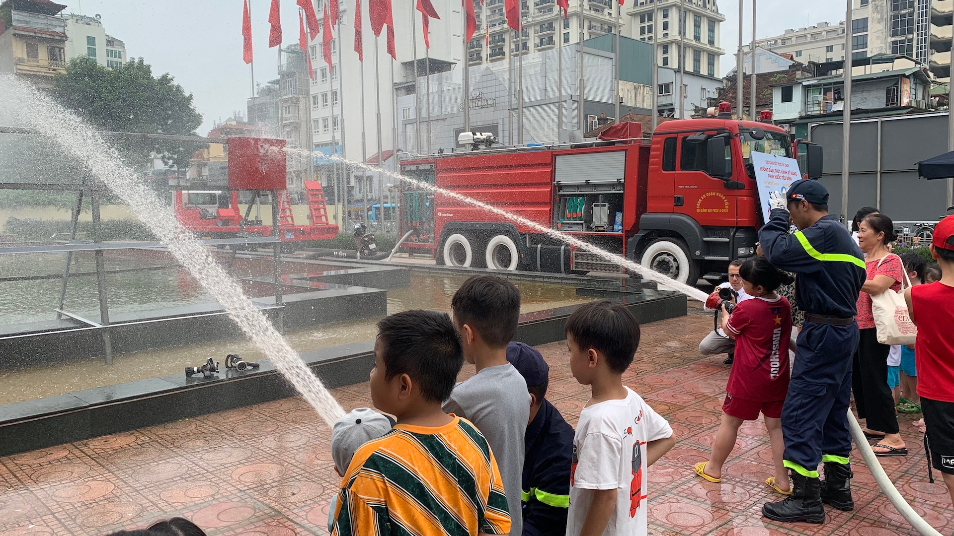 Các em nhỏ được hướng dẫn trải nghiệm phun nước cứu hỏa.