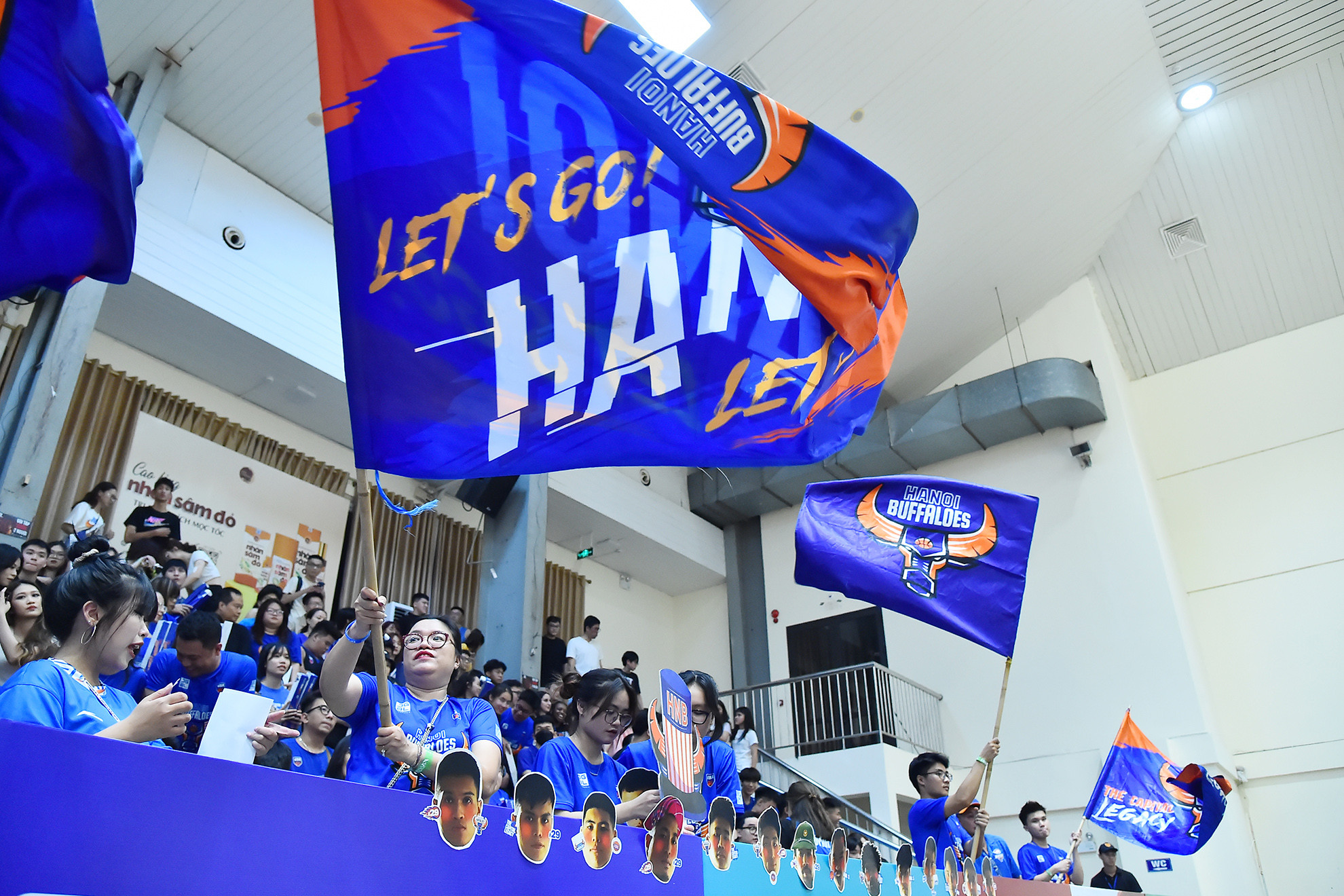 Cổ động viên đội chủ nhà Hanoi Buffaloes với trang phục truyền thống cùng những lá cờ khổ lớn nhuộm xanh một góc khán đài Nhà thi đấu Cầu giấy.