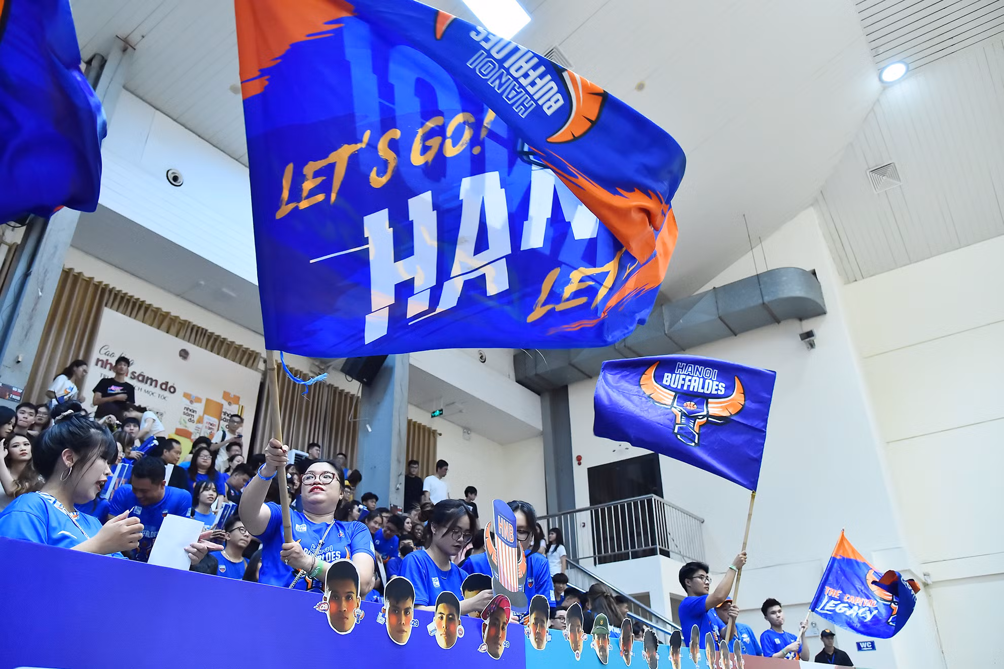 Cổ động viên đội chủ nhà Hanoi Buffaloes với trang phục truyền thống cùng những lá cờ khổ lớn nhuộm xanh một góc khán đài Nhà thi đấu Cầu giấy.
