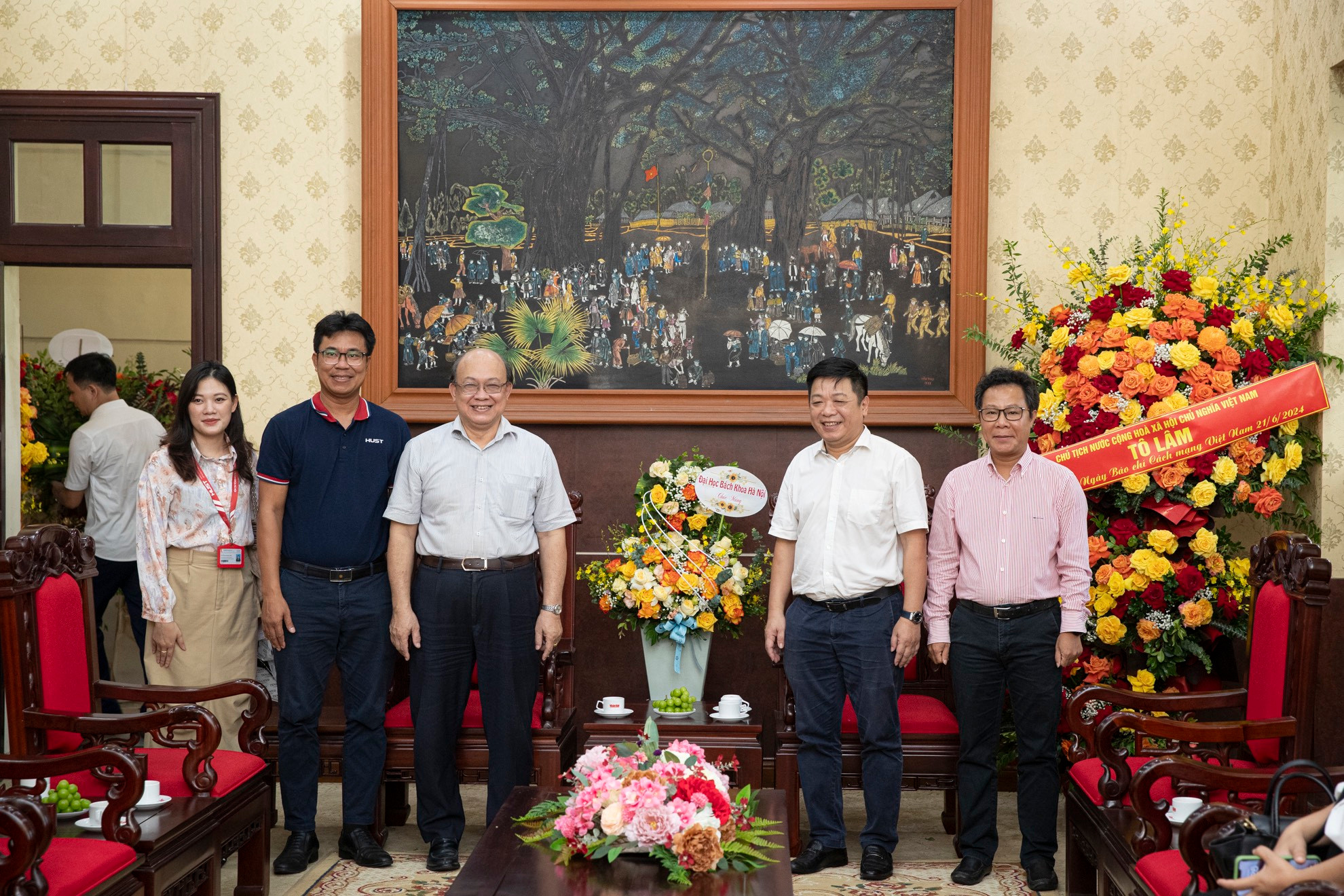 PGS, TS Huỳnh Quyết Thắng, Giám đốc Đại học Bách Khoa Hà Nội tặng lẵng hoa tươi thắm và chụp ảnh lưu niệm cùng Phó Tổng Biên tập Báo Nhân Dân Quế Đình Nguyên.