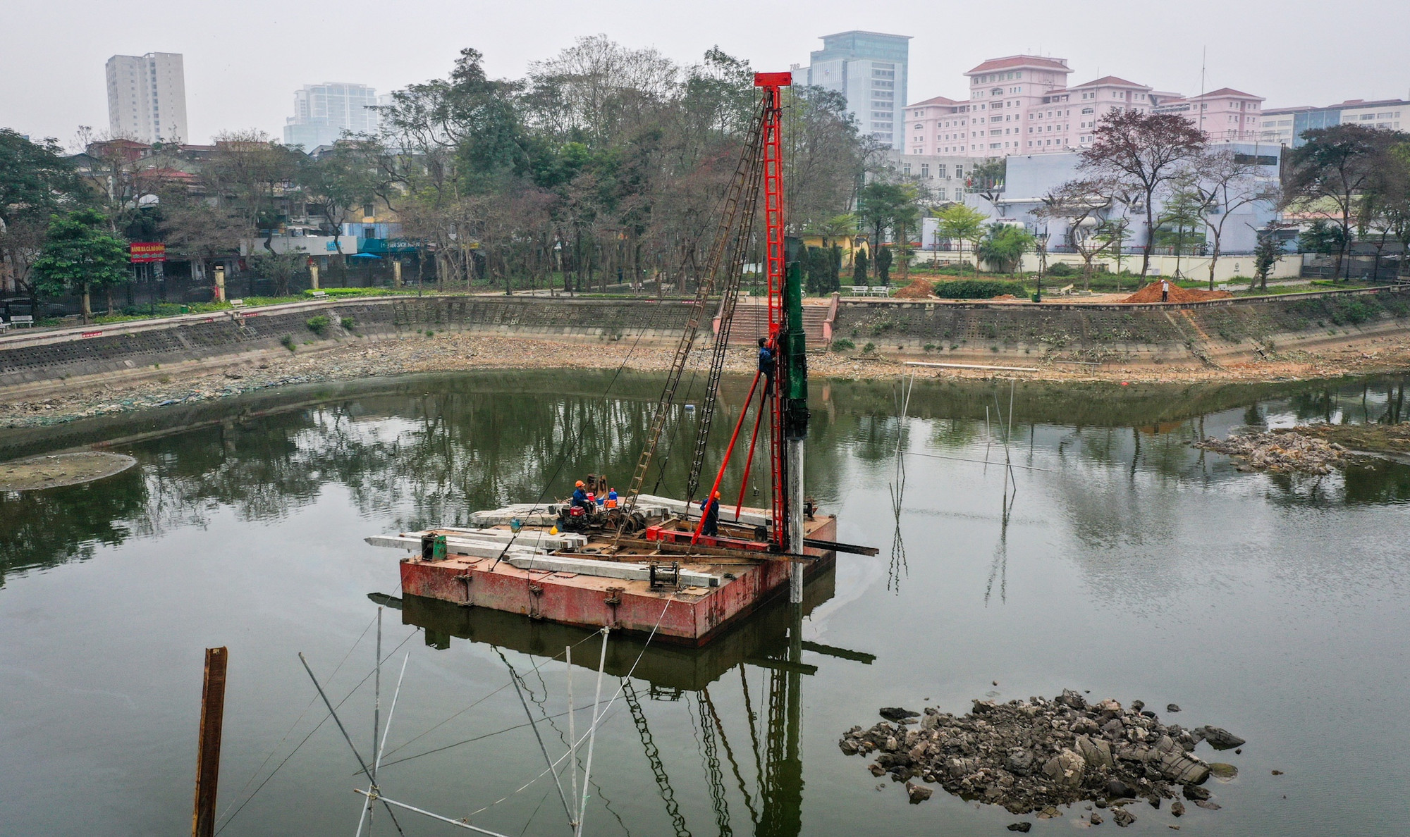 Công nhân làm việc trên lòng hồ Nghĩa Đô. Quá trình này được kỳ vọng sẽ giảm thiểu tình trạng ô nhiễm hiện nay tại khu vực hồ này.