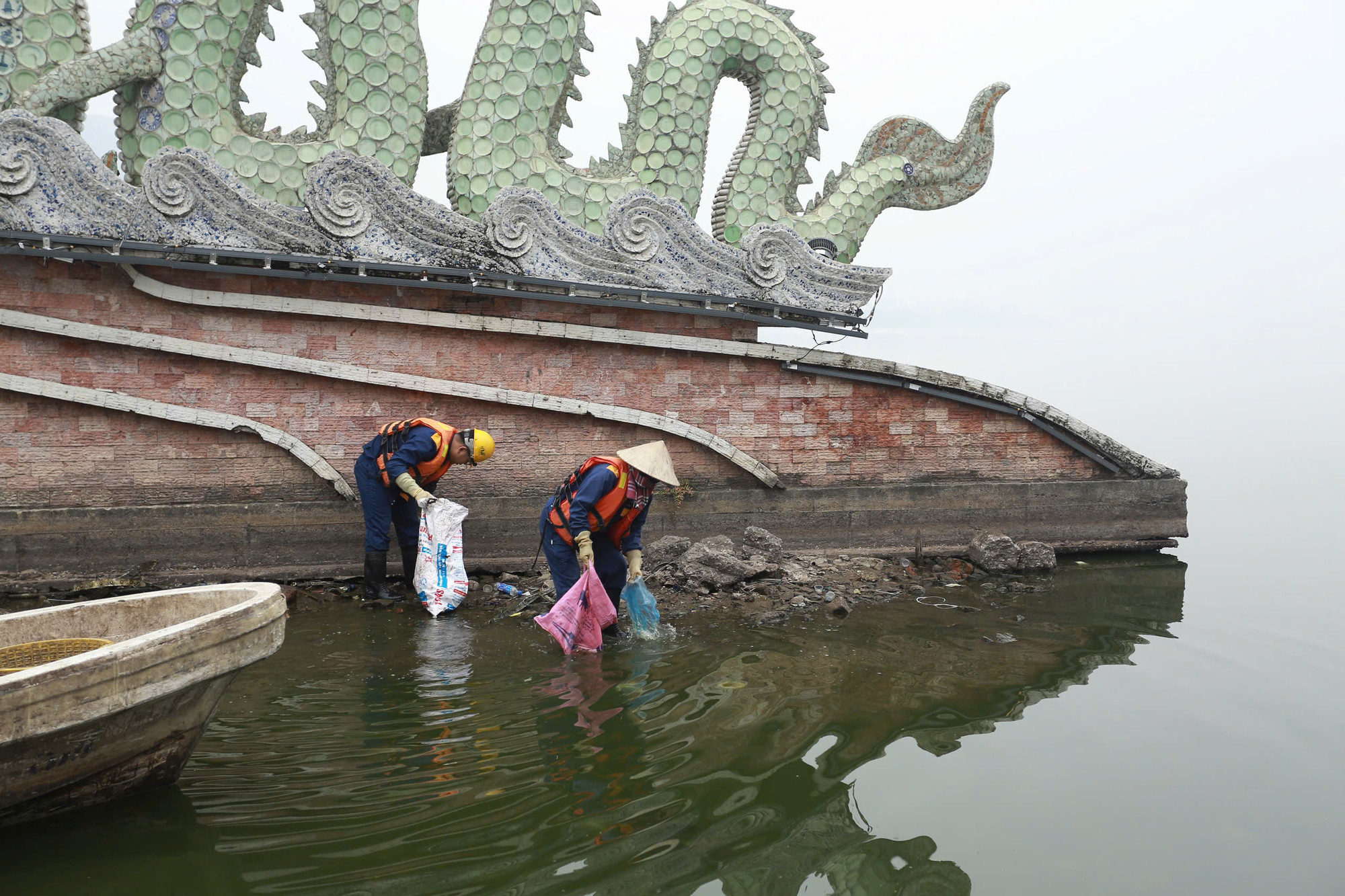 Công nhân của công ty TNHH MTV Thoát nước Hà Nội ứng trực ven hồ Tây để thu gom rác nilon.