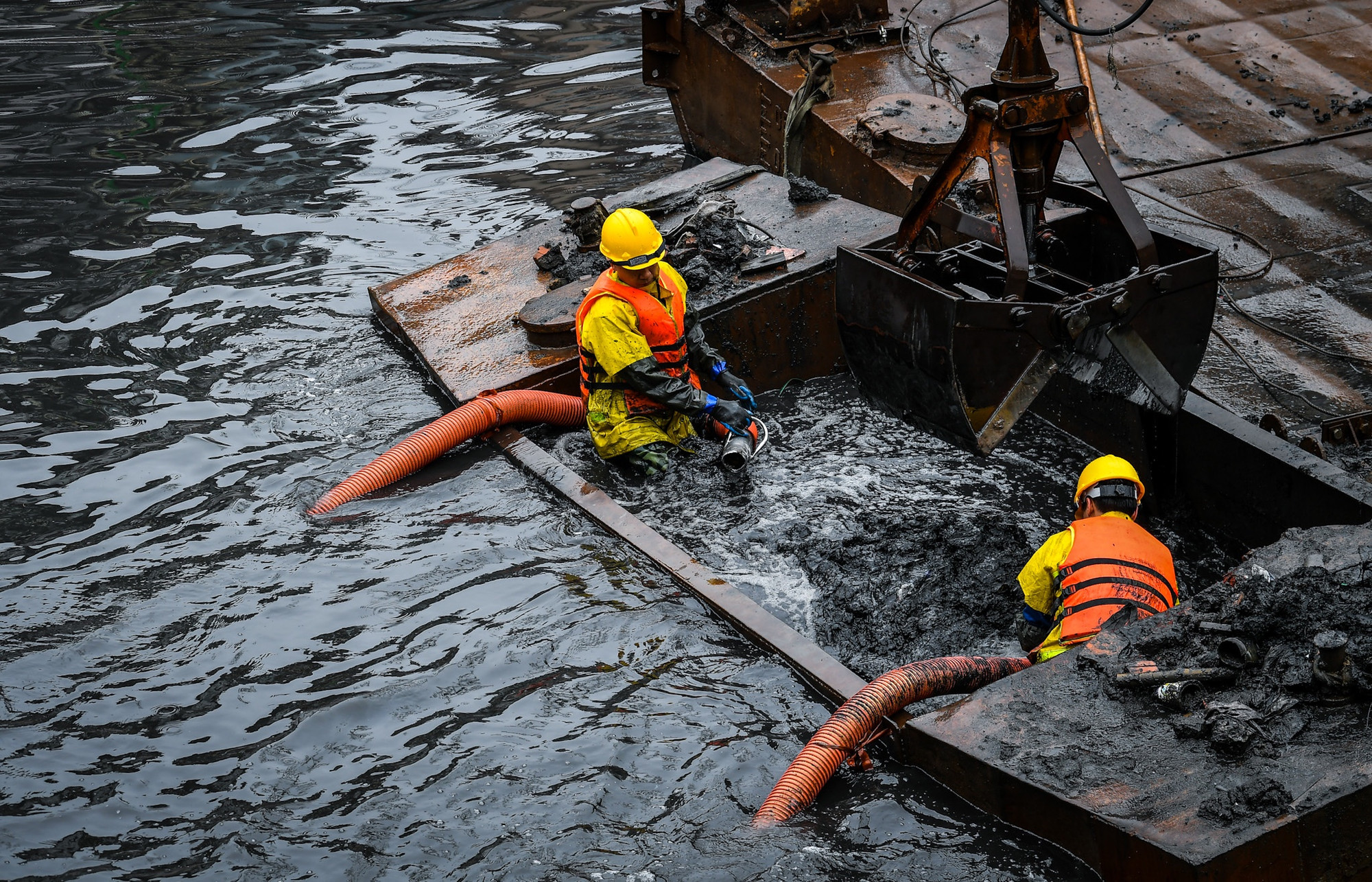 Chốc chốc, tay cẩu 30 tấn sẽ nhấn thuyền chứa xuống sát mặt sông để nước tràn vào. Quá trình này nhằm mục đích "hóa lỏng" bùn, thuận tiện cho việc hút về xe bồn phía trên bờ.