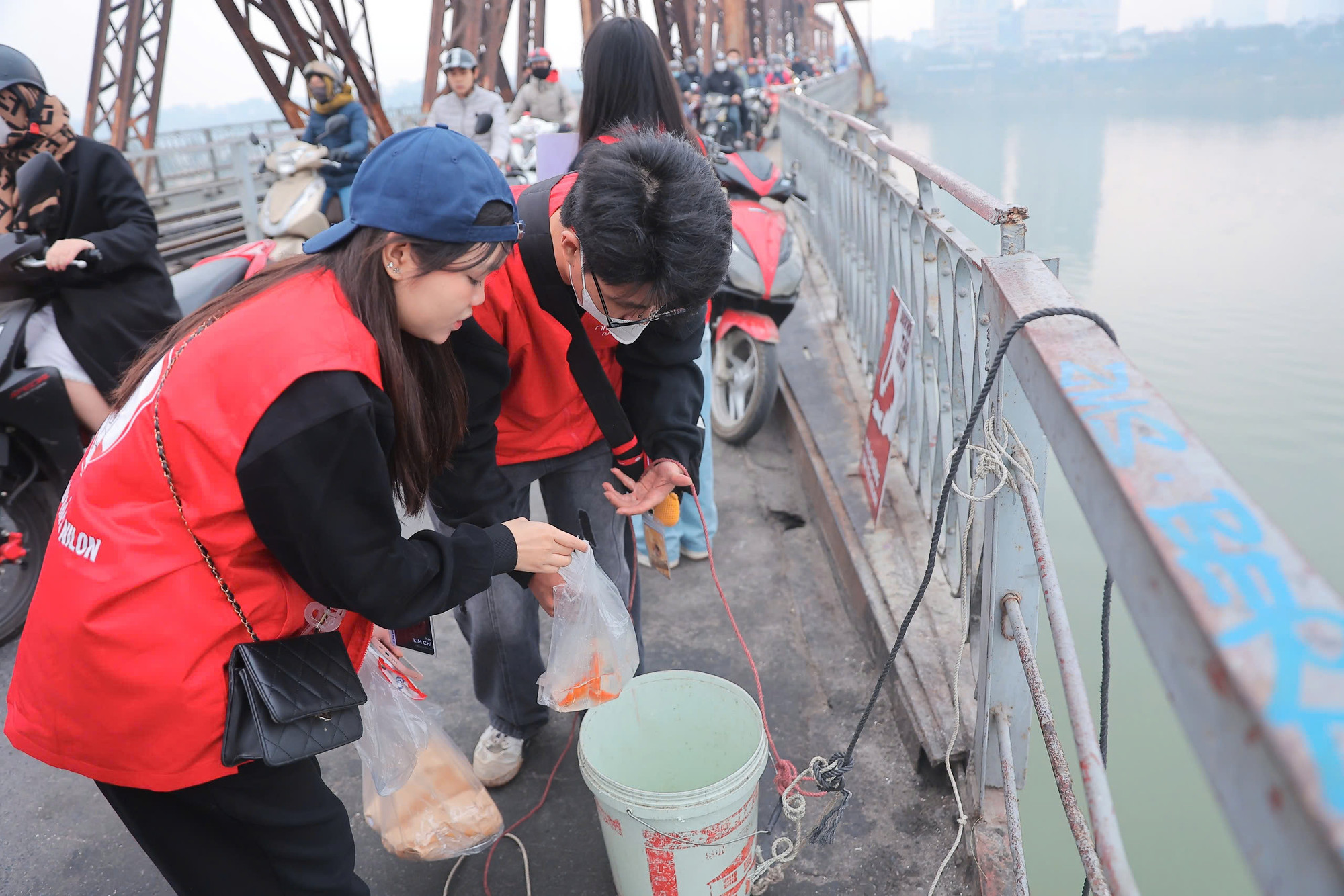 Tại khu vực cầu Long Biên, nhóm tình nguyện viên đã có mặt từ sớm để hỗ trợ người dân thả cá chép, giữ gìn vệ sinh môi trường.