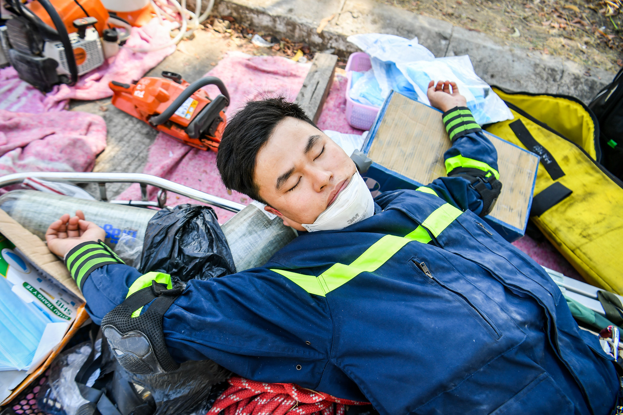 Phút nghỉ ngơi ngắn ngủi ngay trên đống máy móc tại hiện trường tìm kiếm các nạn nhân mất tích do động đất.