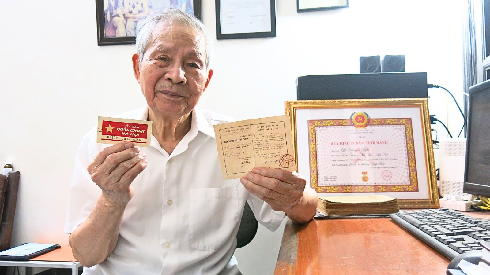 Cựu cán bộ công an Lê Nguyên Diệu bên tấm thẻ thông hành và chứng minh thư do Ủy ban Quân chính thành phố Hà Nội cấp năm 1954. (Ảnh: PHƯƠNG NAM)