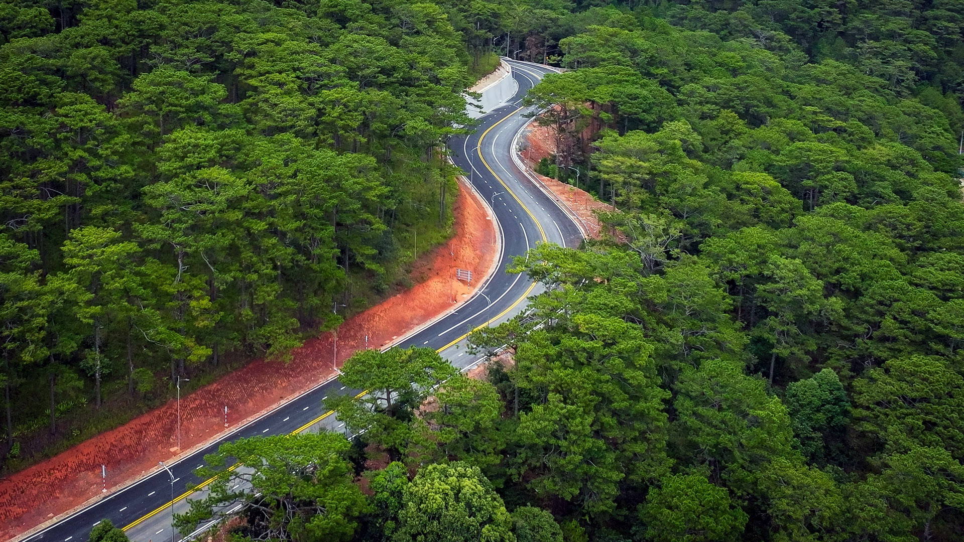 Đèo Prenn đi qua địa hình đồi núi, với những đường cong thấp thoáng dưới tán rừng thông lãng mạn.