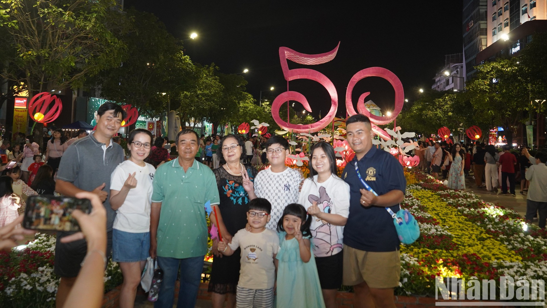 Nhiều gia đình ghi lại kỷ niệm trước tấm biển chào mừng năm mới được trưng bày tại đường hoa Nguyễn Huệ Ất Tỵ 2025.