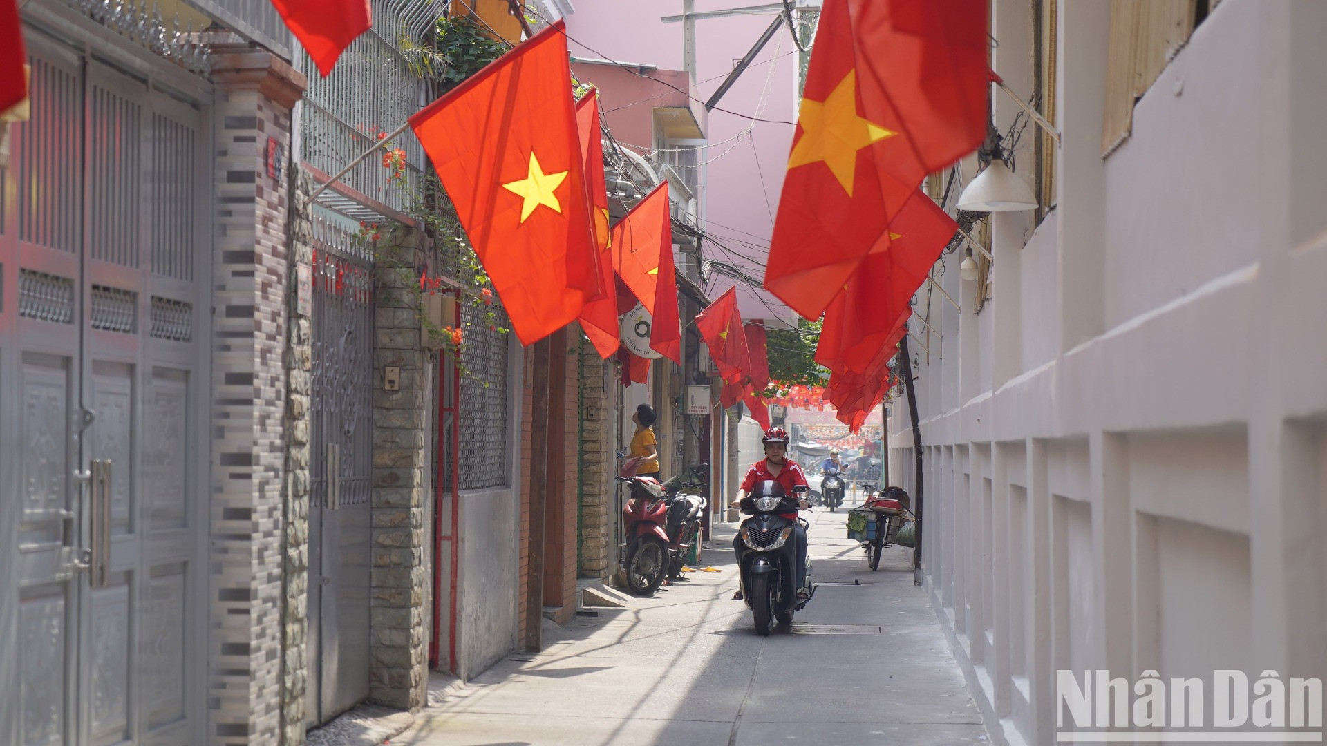 Cách đó không xa không gian Tết Việt ấm cúng và rộn ràng những chiếc lá cờ Tổ quốc được treo từ ngoài hẻm vào tận cửa nhà dân.