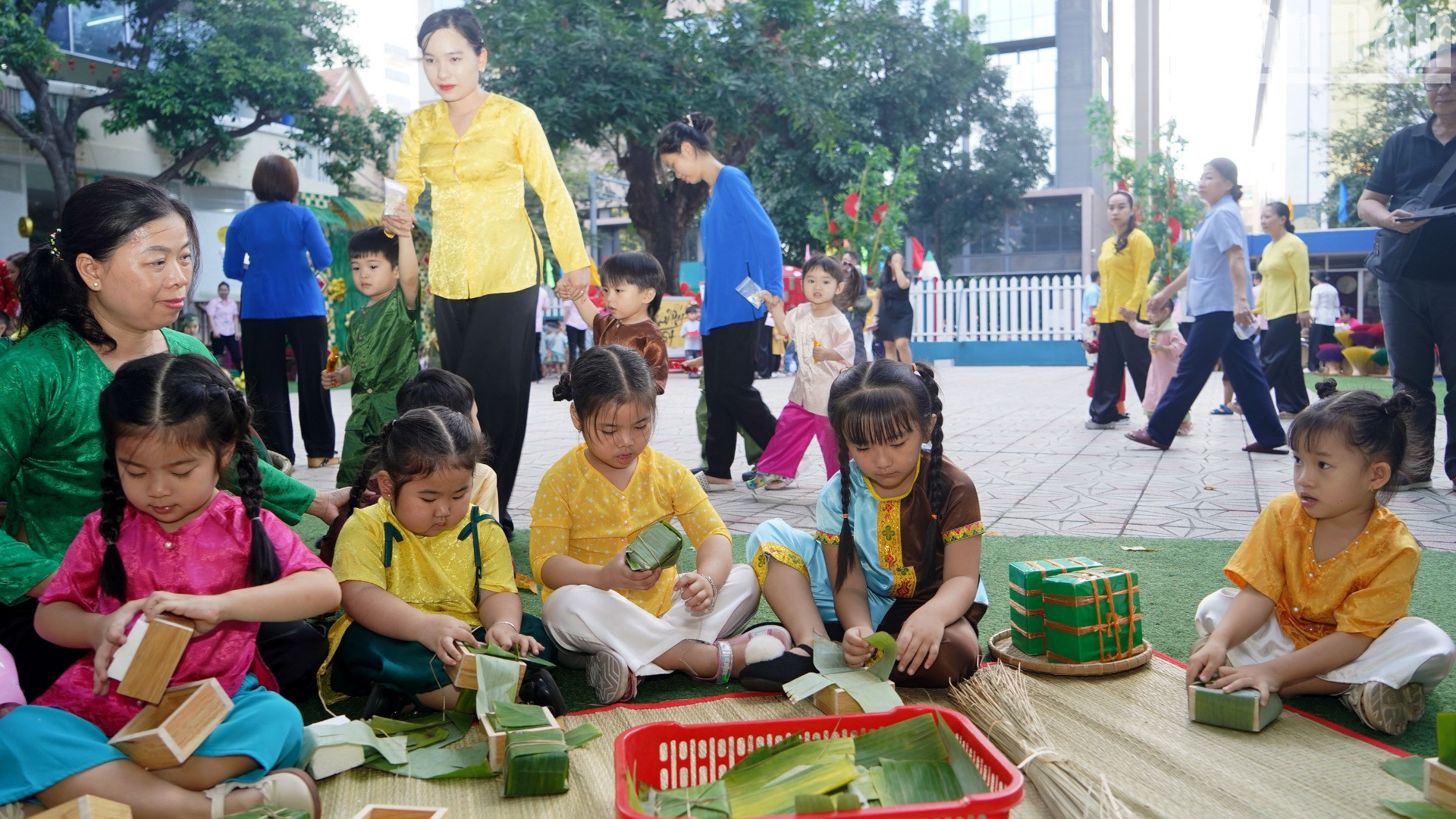 Các em nhỏ chăm chú quan sát, lắng nghe và học theo cô giáo gói bánh.