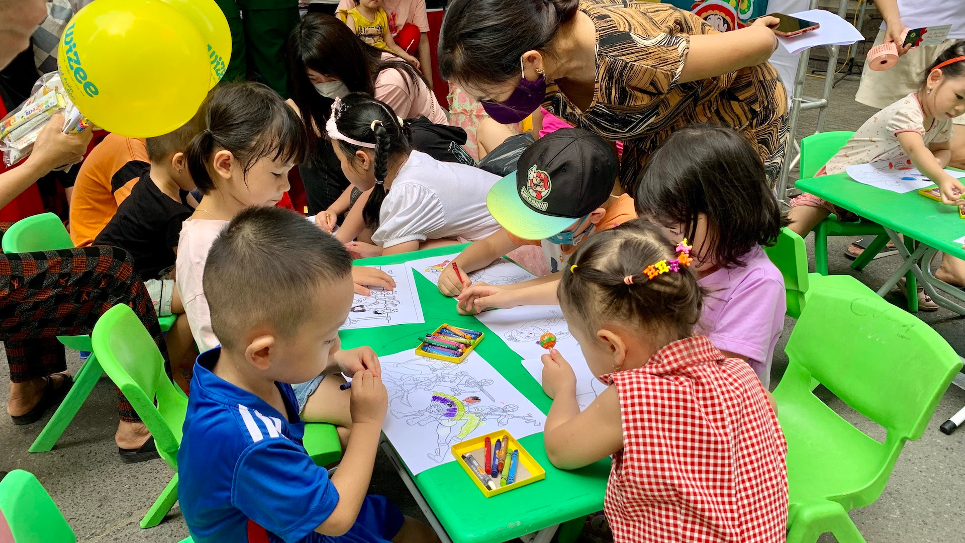 Các em nhỏ tham gia hoạt động tô, vẽ tranh do một gian hàng tổ chức miễn phí.