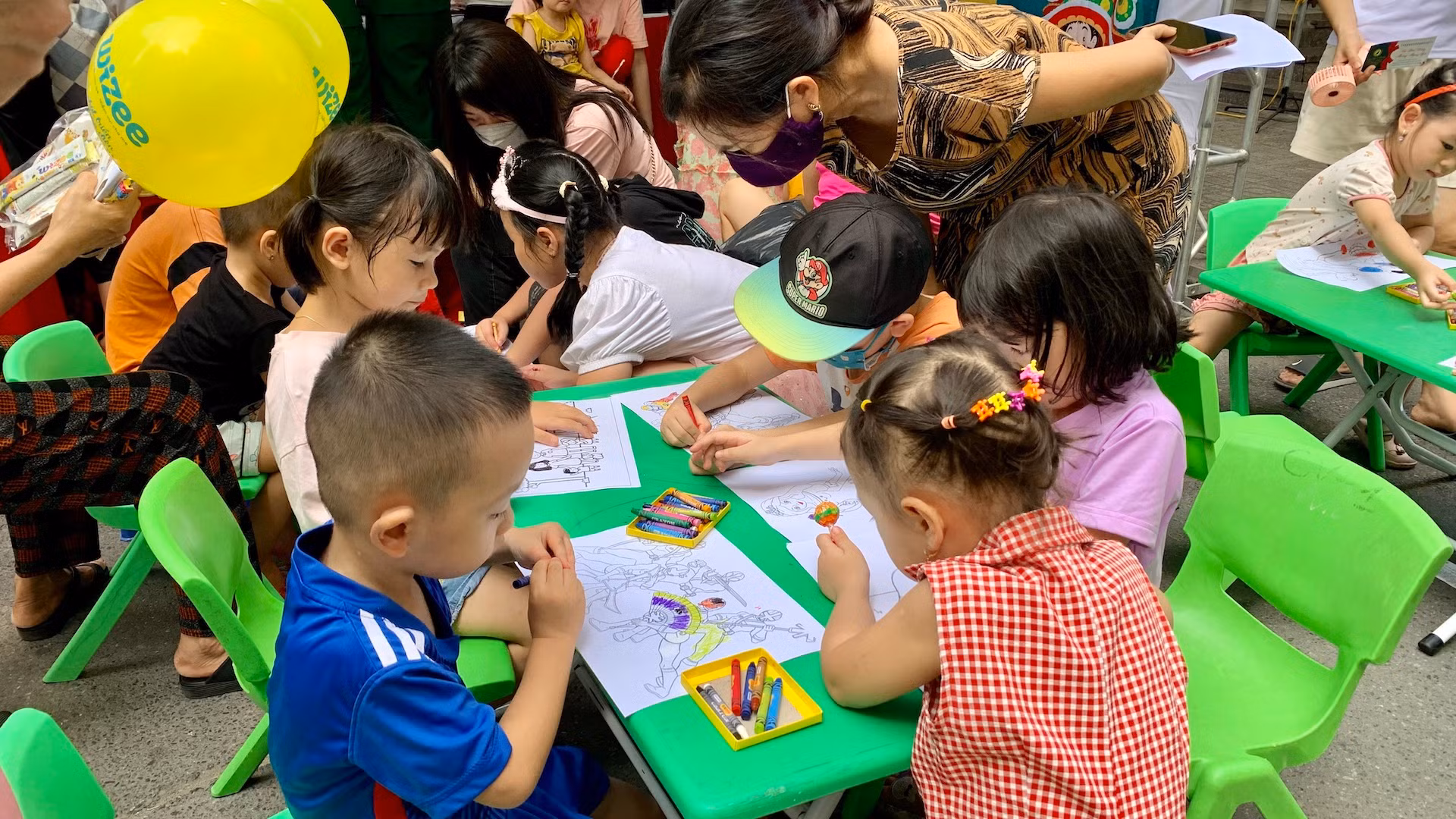 Các em nhỏ tham gia hoạt động tô, vẽ tranh do một gian hàng tổ chức miễn phí.