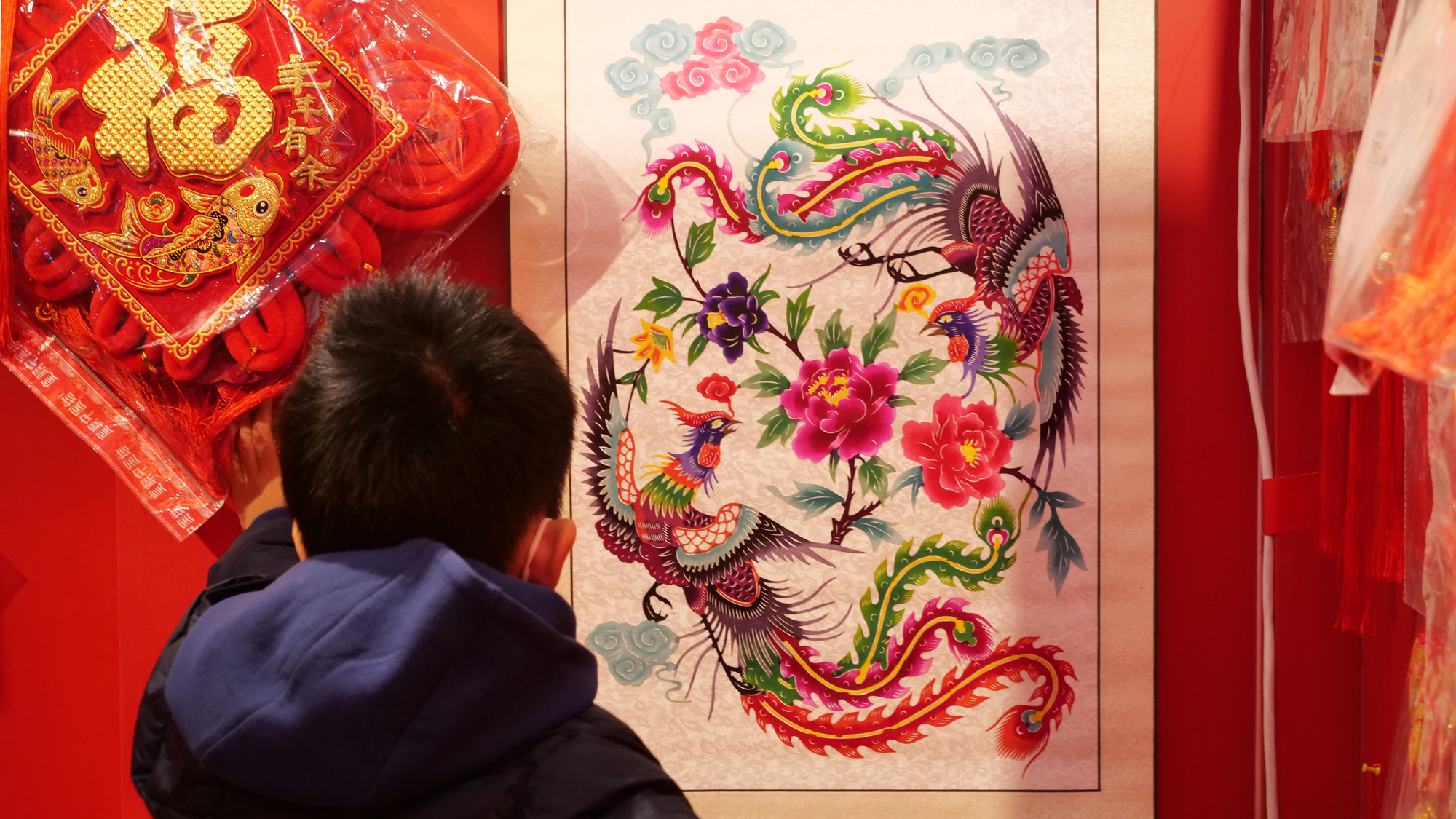 Một cậu bé say sưa ngắm tranh Tết truyền thống "Song phượng quần tụ mẫu đơn". Một cậu bé say sưa ngắm tranh Tết truyền thống "Song phượng quần tụ mẫu đơn".