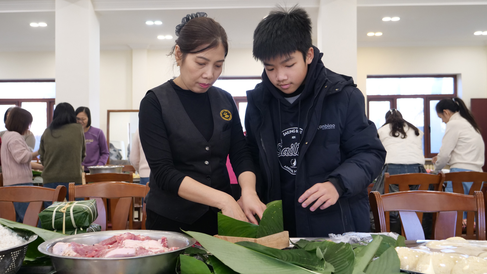 Hướng dẫn thế hệ trẻ gói bánh chưng.