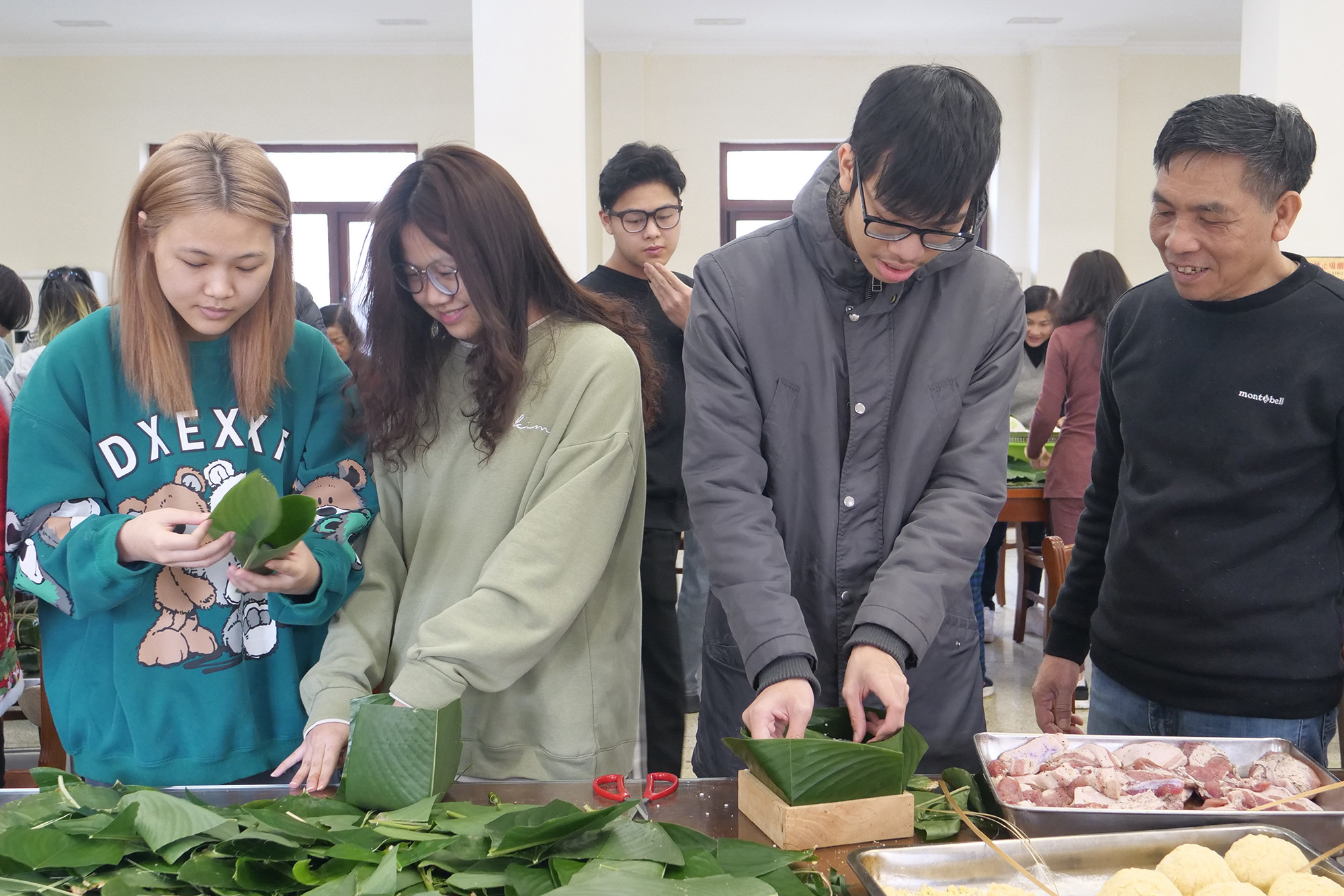 Các thanh niên trải nghiệm gói bánh chưng.