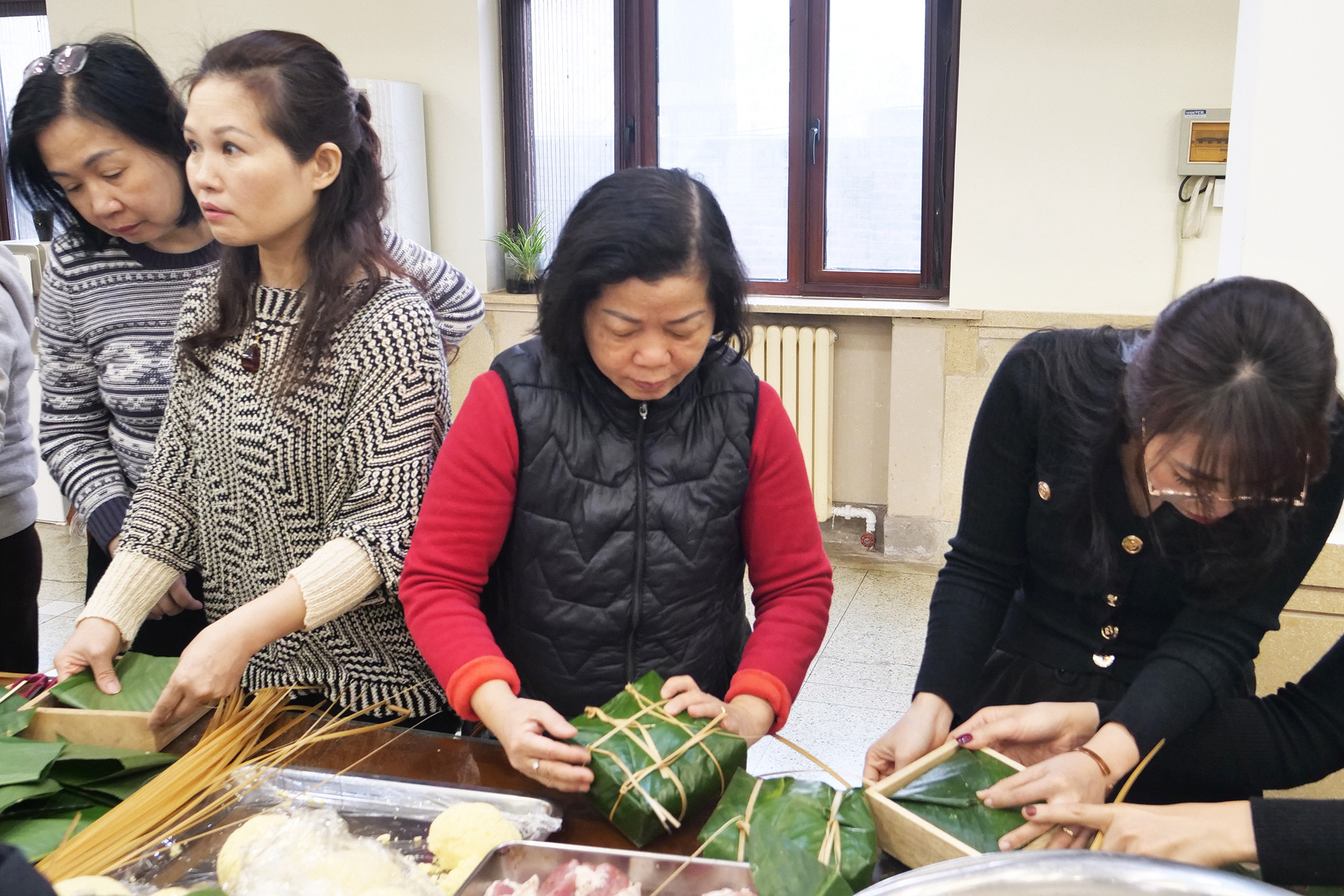 Phu nhân Đại sứ (giữa) tham gia gói bánh chưng.