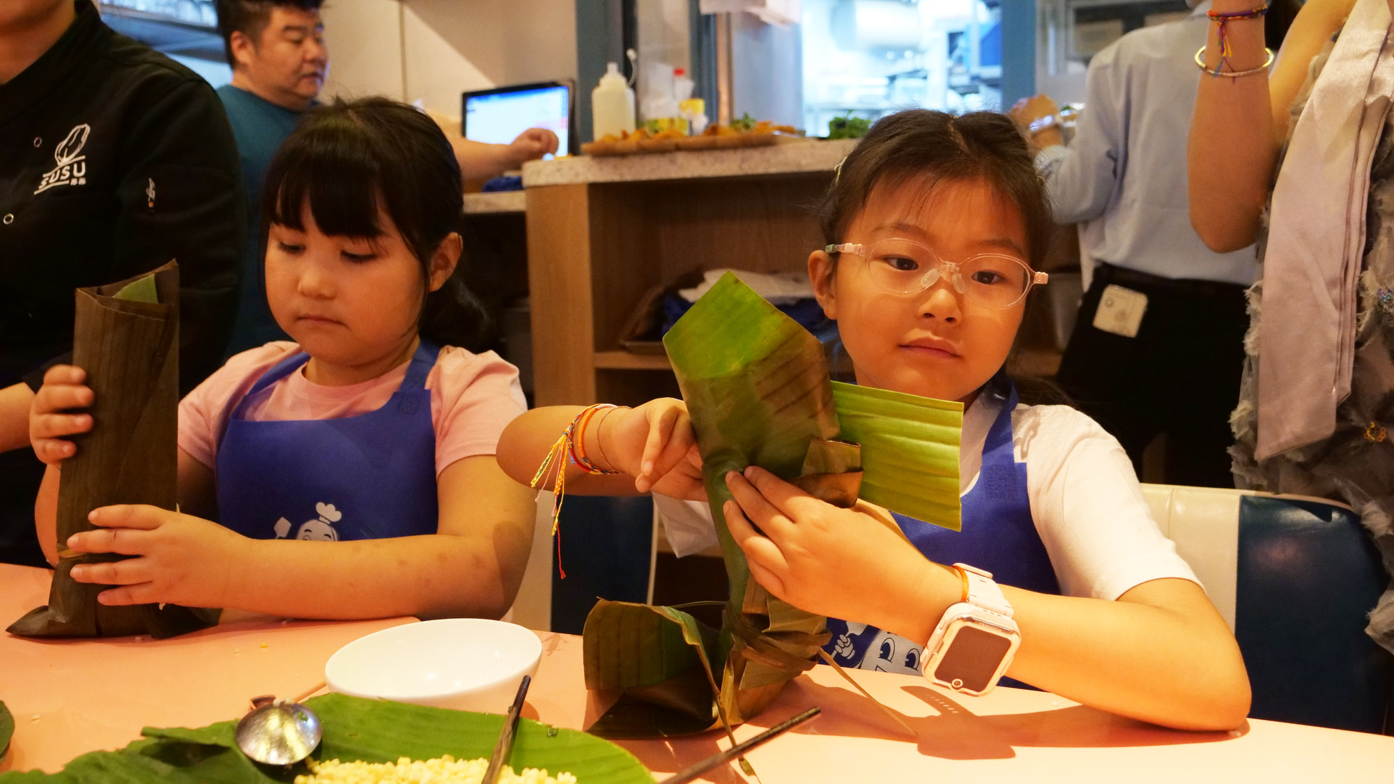 Một thiếu nhi thủ đô Bắc Kinh quan sát và trải nghiệm tự gói bánh chưng Việt Nam.