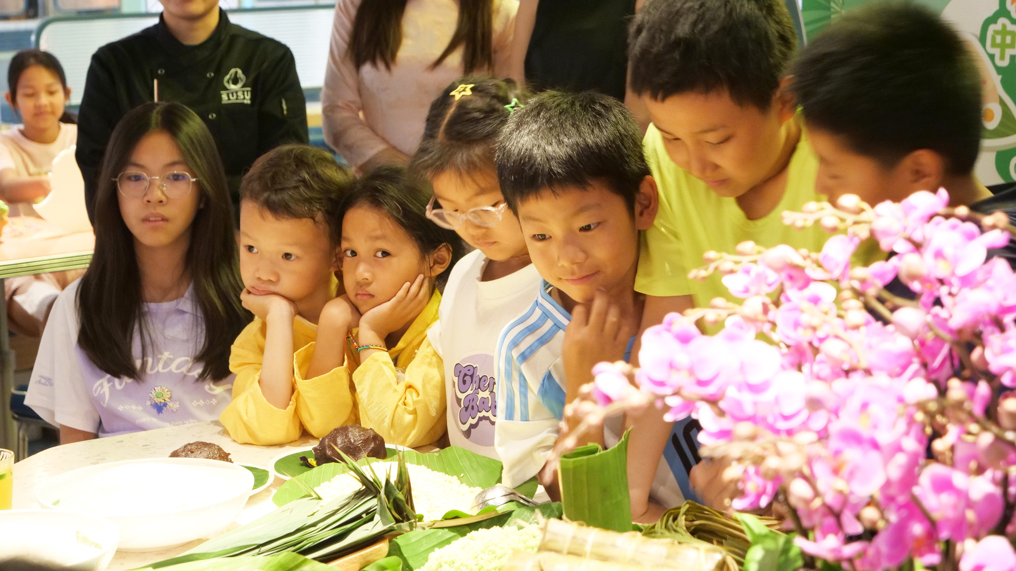 Các cháu thiếu nhi Việt Nam và Trung Quốc vừa nghe vừa háo hức chờ đợi trải nghiệm gói bánh ú, bánh chưng.