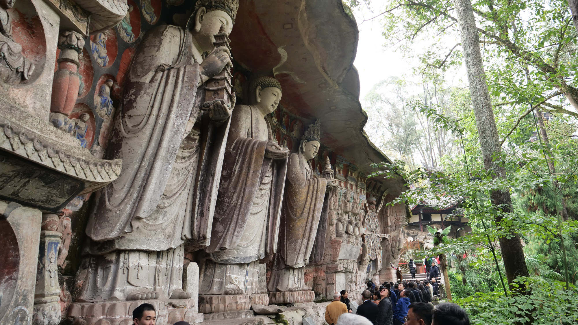 Tượng tam thánh gồm 3 pho tượng Tỳ Lô Giá Na Phật (giữa) Phổ Hiền bồ tát (trái) và Văn Thù bồ tát (phải) cao 7m, khoác áo cà sa đứng trên đài sen, thân hơi ngả về phía trước, cúi đầu ngó xuống chúng sinh. Đây cũng là kiệt tác của nghệ thuật điêu khắc đá khi các nghệ nhân điêu khắc thời xưa đã giải quyết bài toán trọng lực hàng chục tấn của bức tượng nghiêng về phía trước bằng cách chạm khắc áo cà sa thành trụ đỡ chịu lực mà vẫn không mất đi nét sinh động, uyển chuyển của bức tượng.