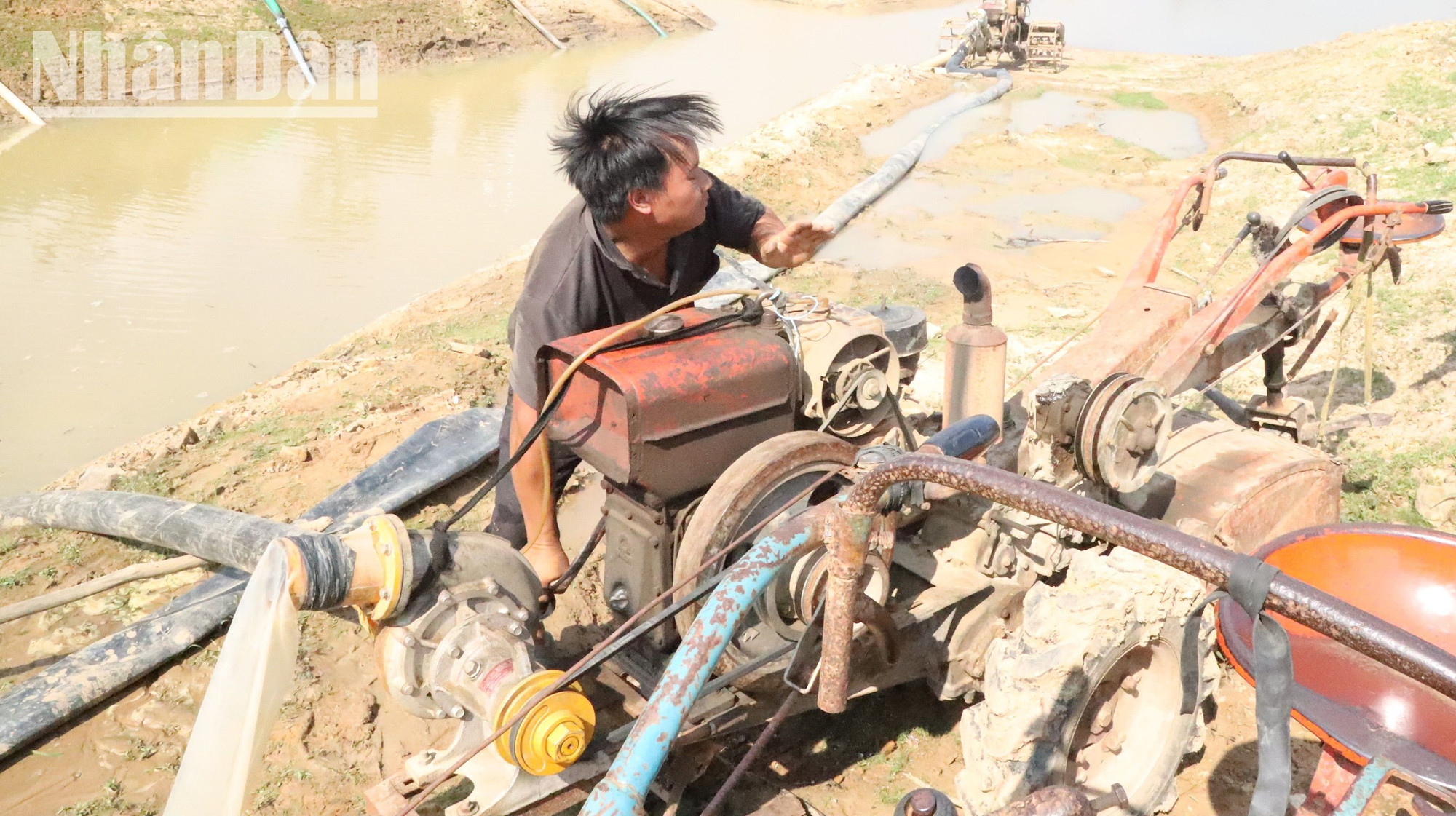 Một người nông dân đang nỗ lực quay máy bơm nước chống hạn.